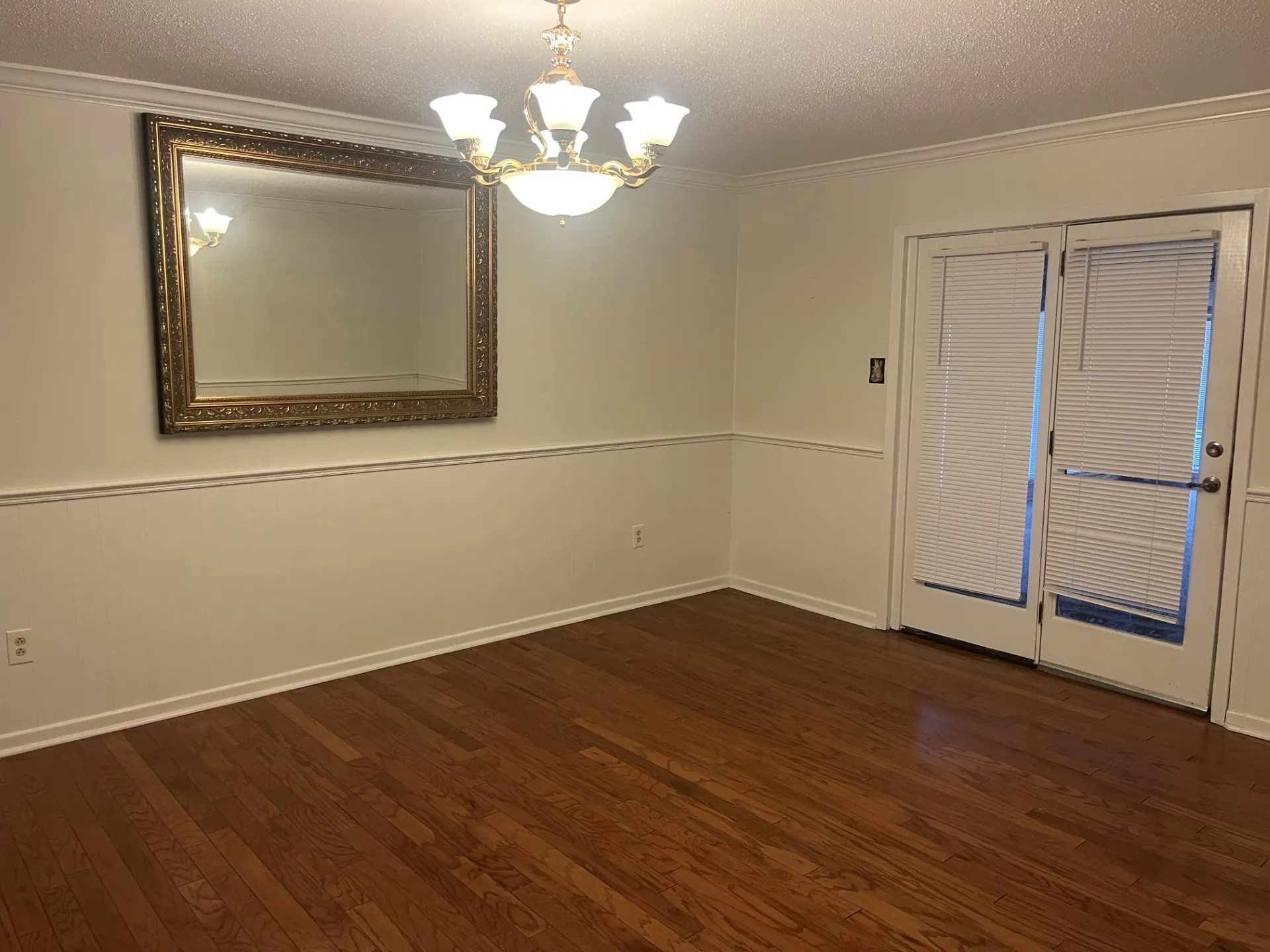 Wood-finish flooring, chair rail molding, crown molding, and a five-light chandelier