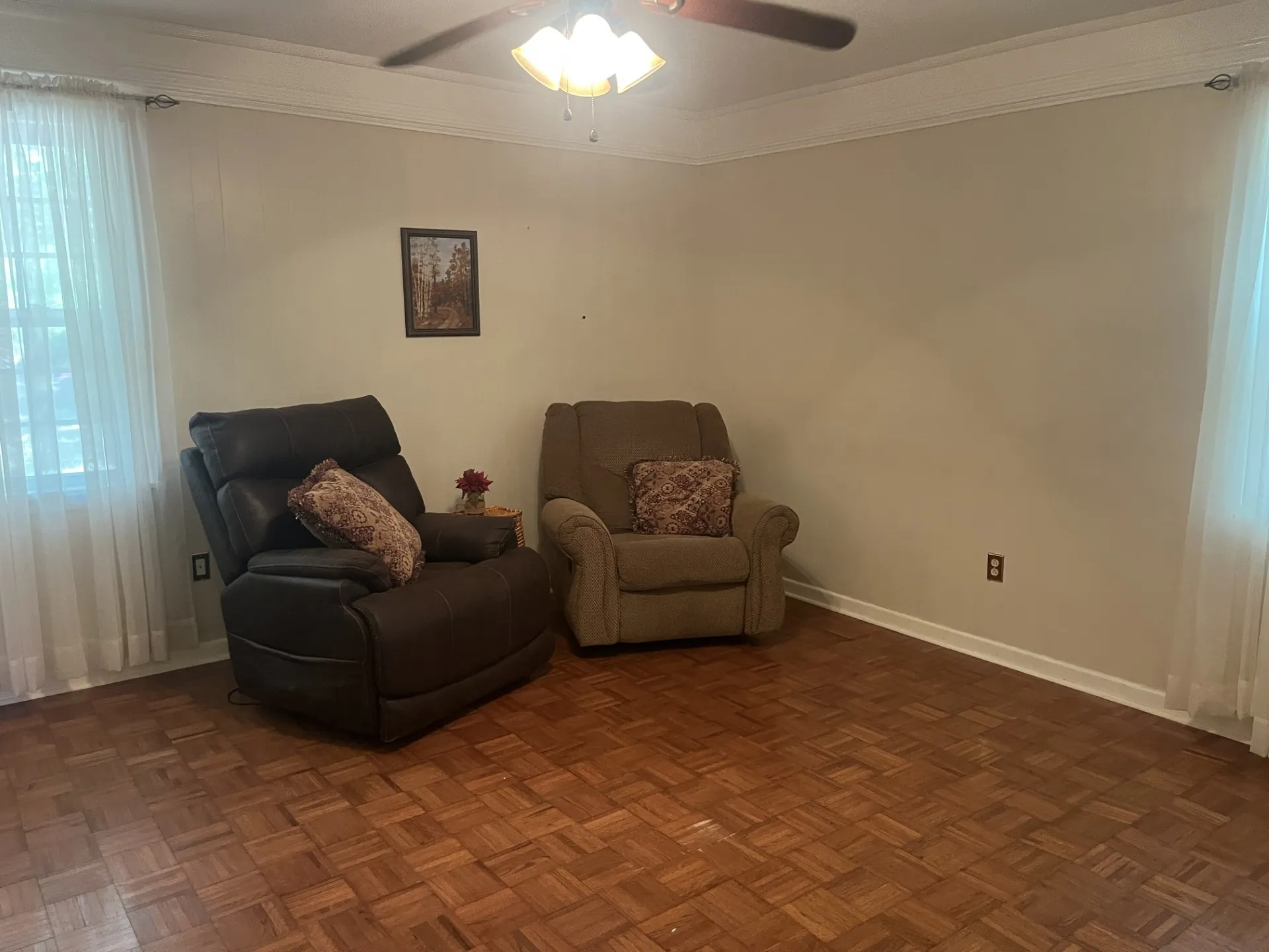 Wood-finish flooring with a parquet pattern, crown molding, and a ceiling fan with integrated lighting