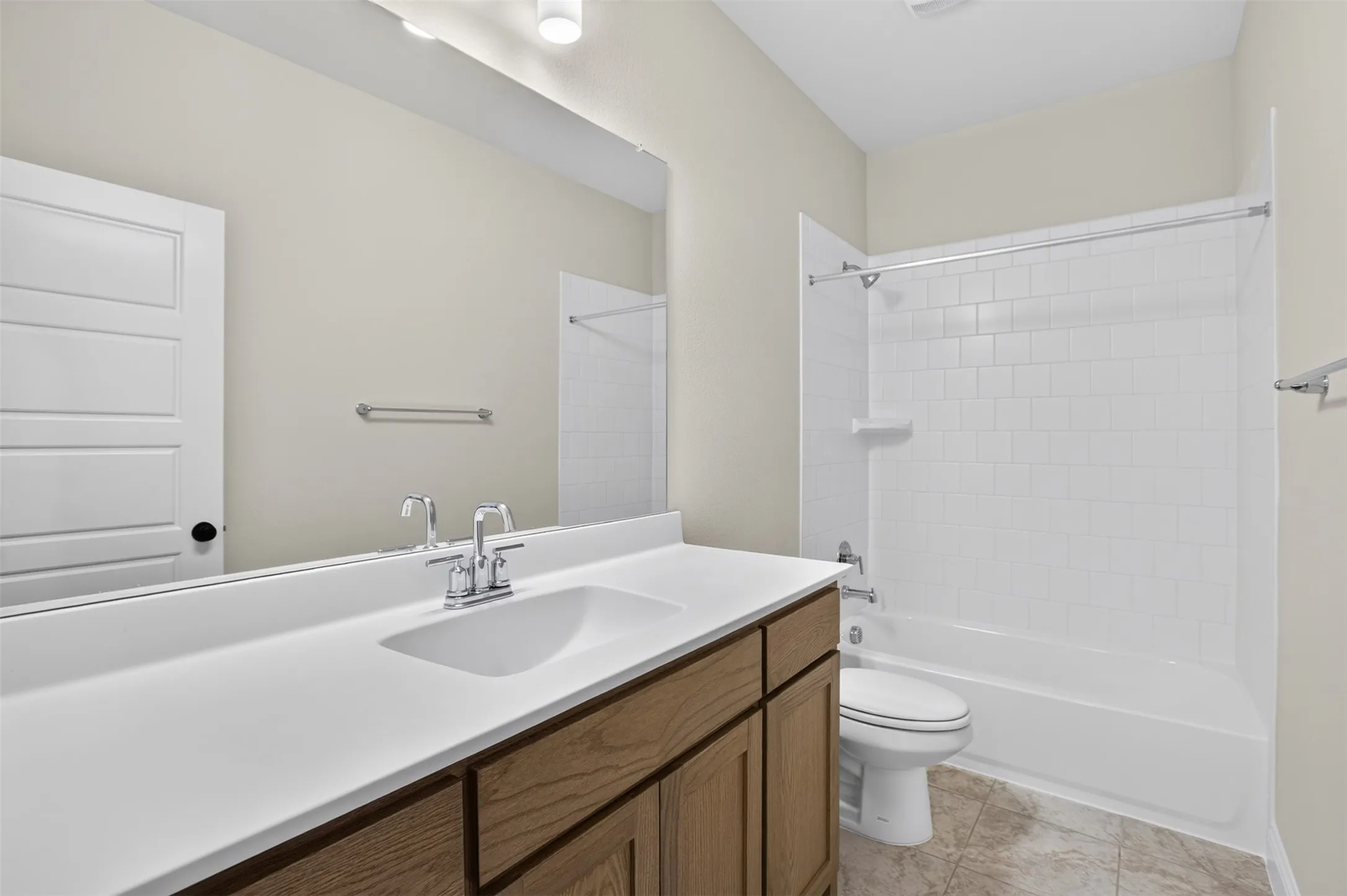 Wood-finish vanity with an integrated white sink, chrome faucet, and expansive wall mirror