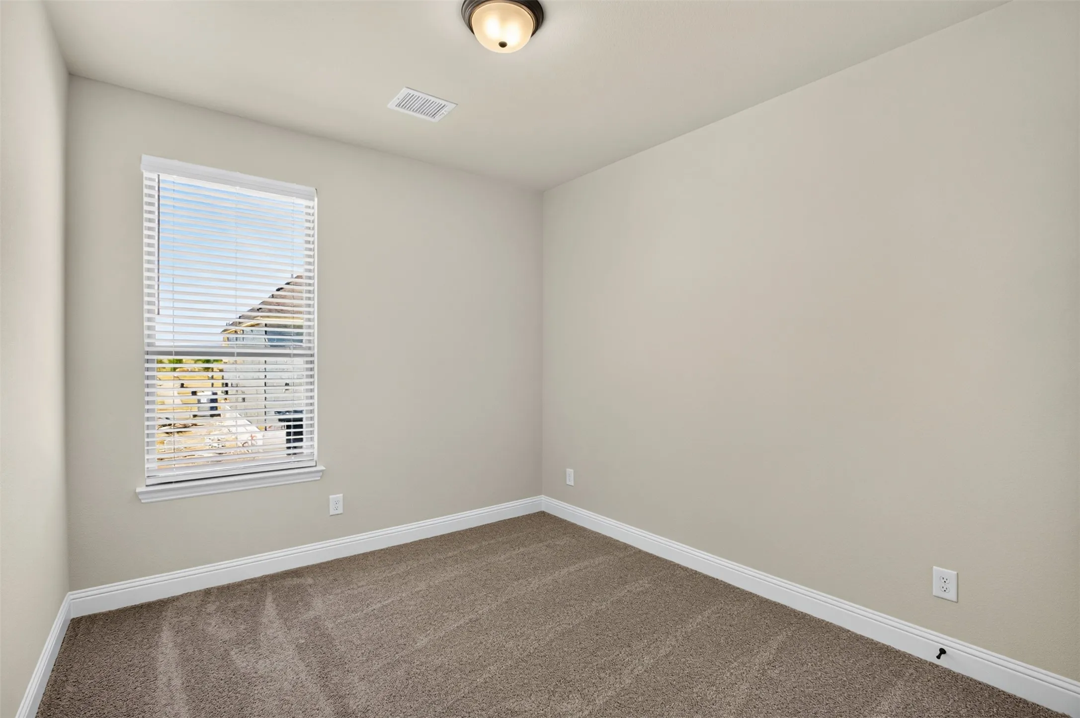 Carpeted flooring, neutral wall tones, window with horizontal blinds, and a flush mount ceiling light