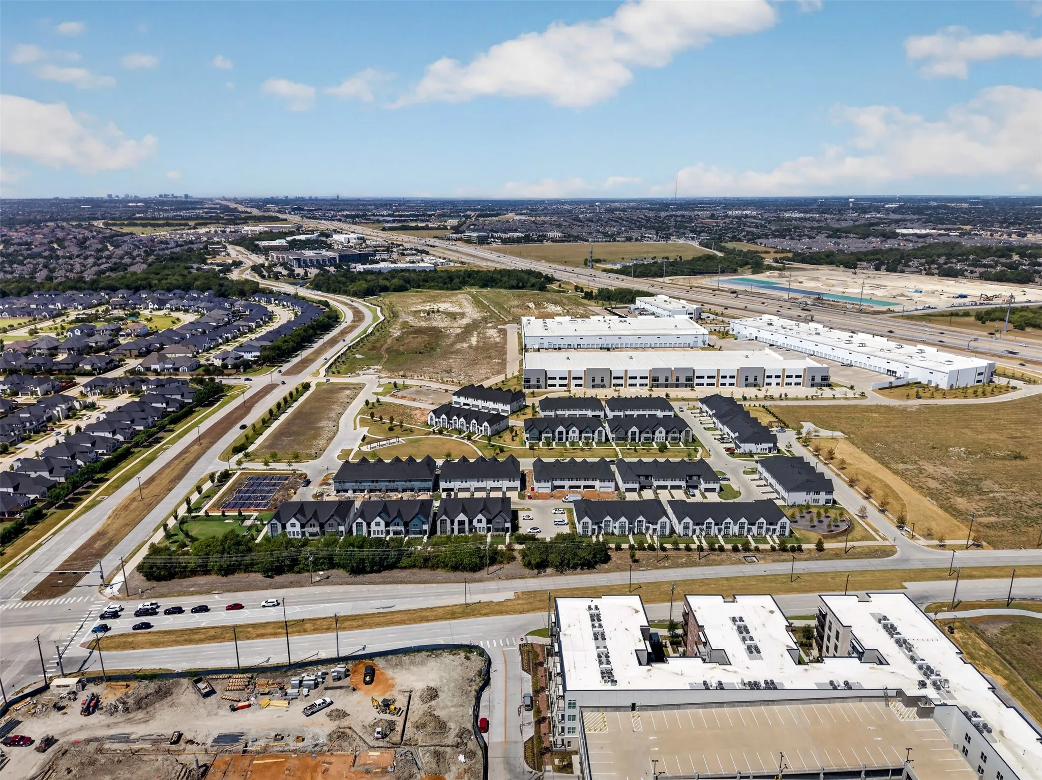 Aerial perspective showcasing a residential development with multiple unit types, established suburban neighborhoods, commercial buildings, and major roadways