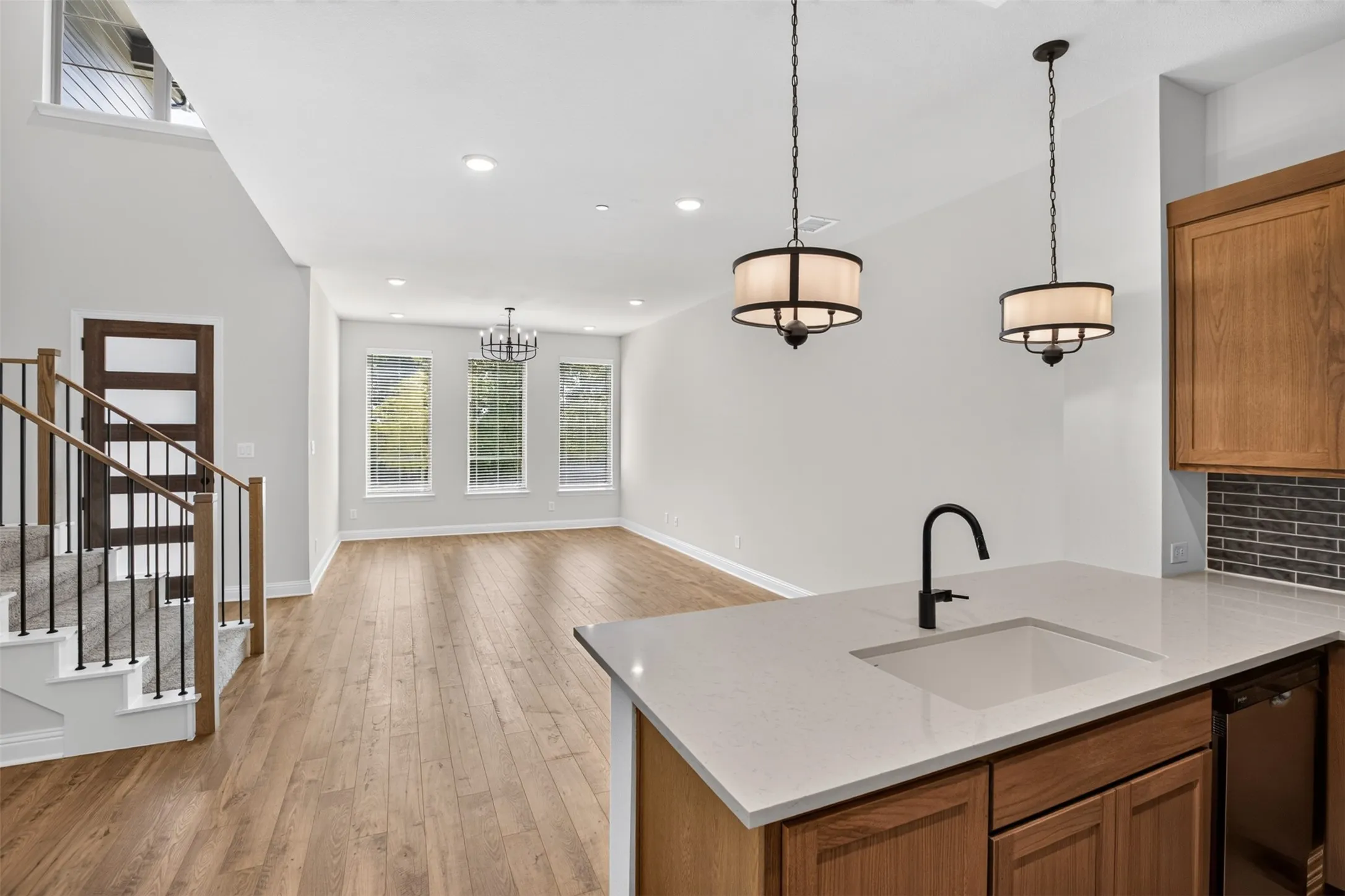 Open-concept living area with wood-finish flooring, recessed lighting, and a modern chandelier