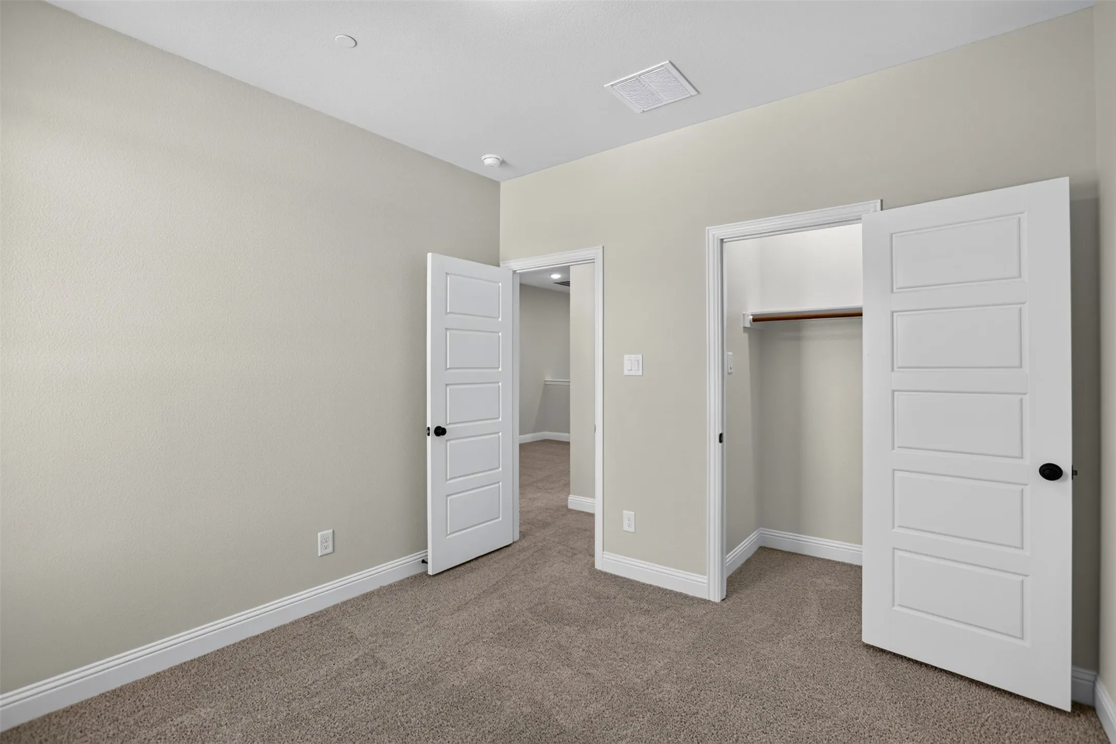 Neutral-toned carpeting, white interior doors with black hardware, recessed ceiling lighting, and a closet with built-in hanging rod