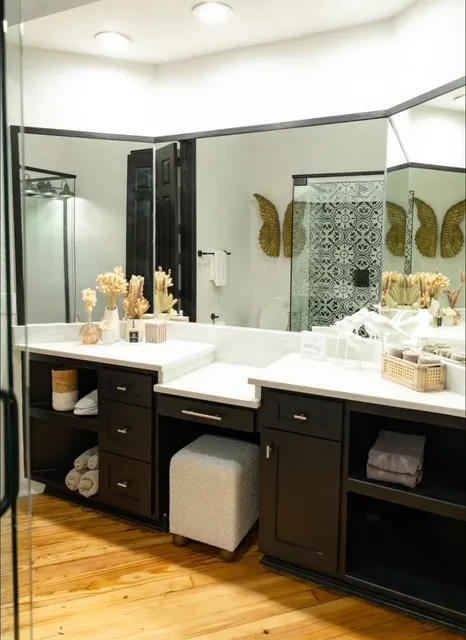 Dual vanity with white countertops, dark wood cabinetry, wood-finish flooring, recessed lighting, and a glass-enclosed shower with patterned tile