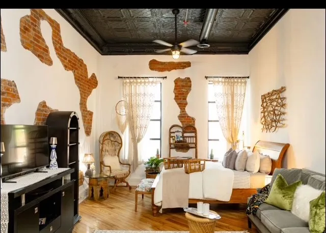 Exposed brick wall accents, pressed tin ceiling, wood-finish flooring, industrial-style ceiling fan, and large windows with transom details