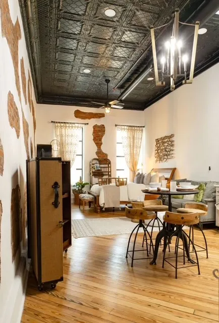 Exposed brick wall accents, wood-finish flooring, a decorative metal ceiling, recessed lighting, and a contemporary chandelier
