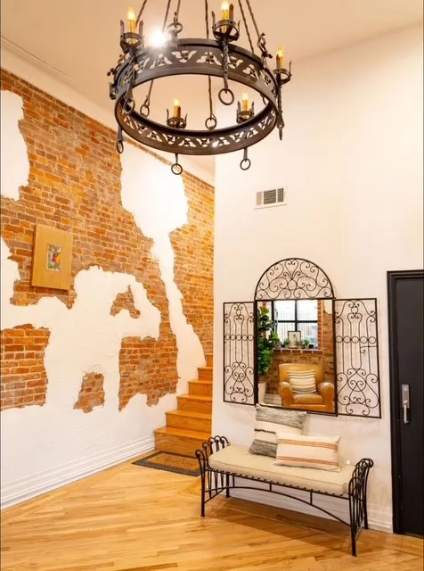 Exposed brick accent wall, wood-finish flooring, and a decorative wrought iron chandelier