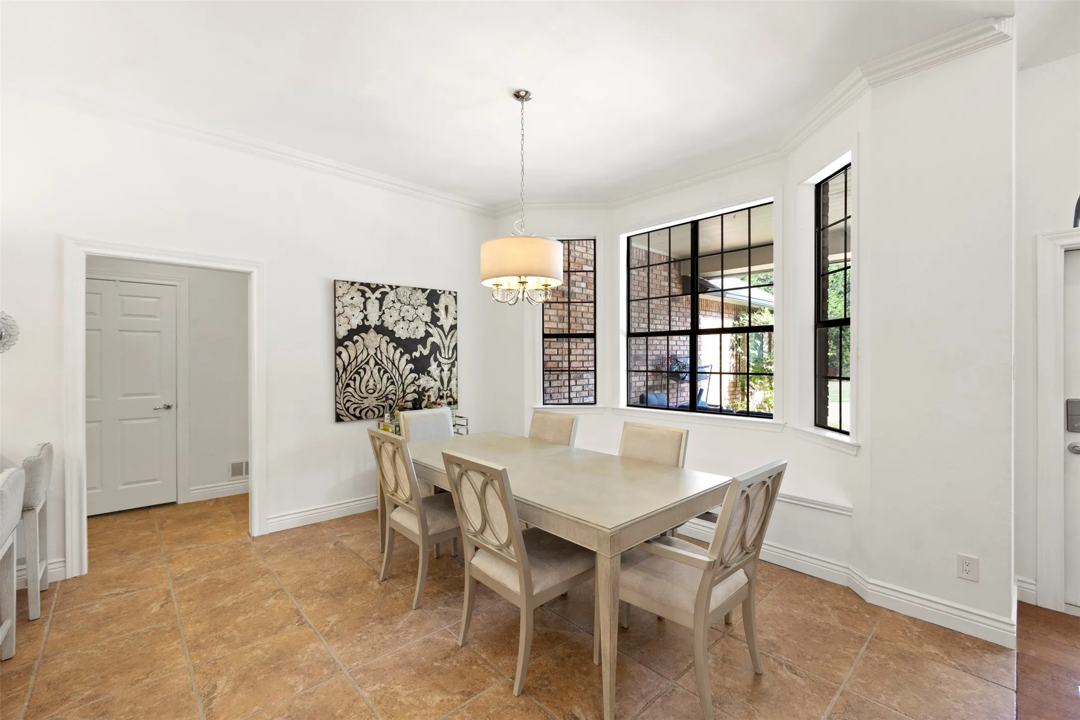 Bay window with black-framed grid panes, crown molding, drum pendant light fixture, and tile flooring