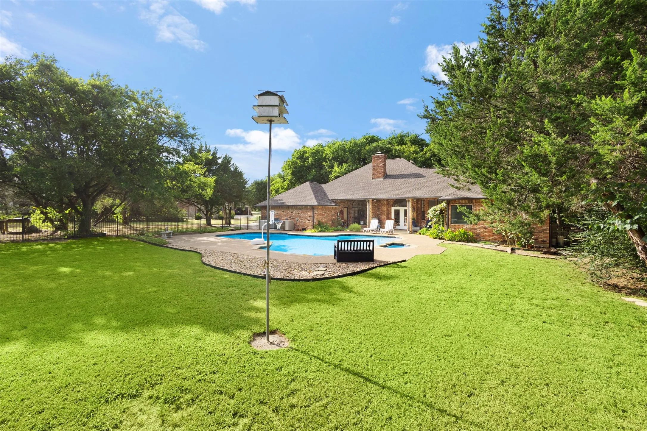 Expansive backyard with a manicured lawn, inground swimming pool, and mature trees