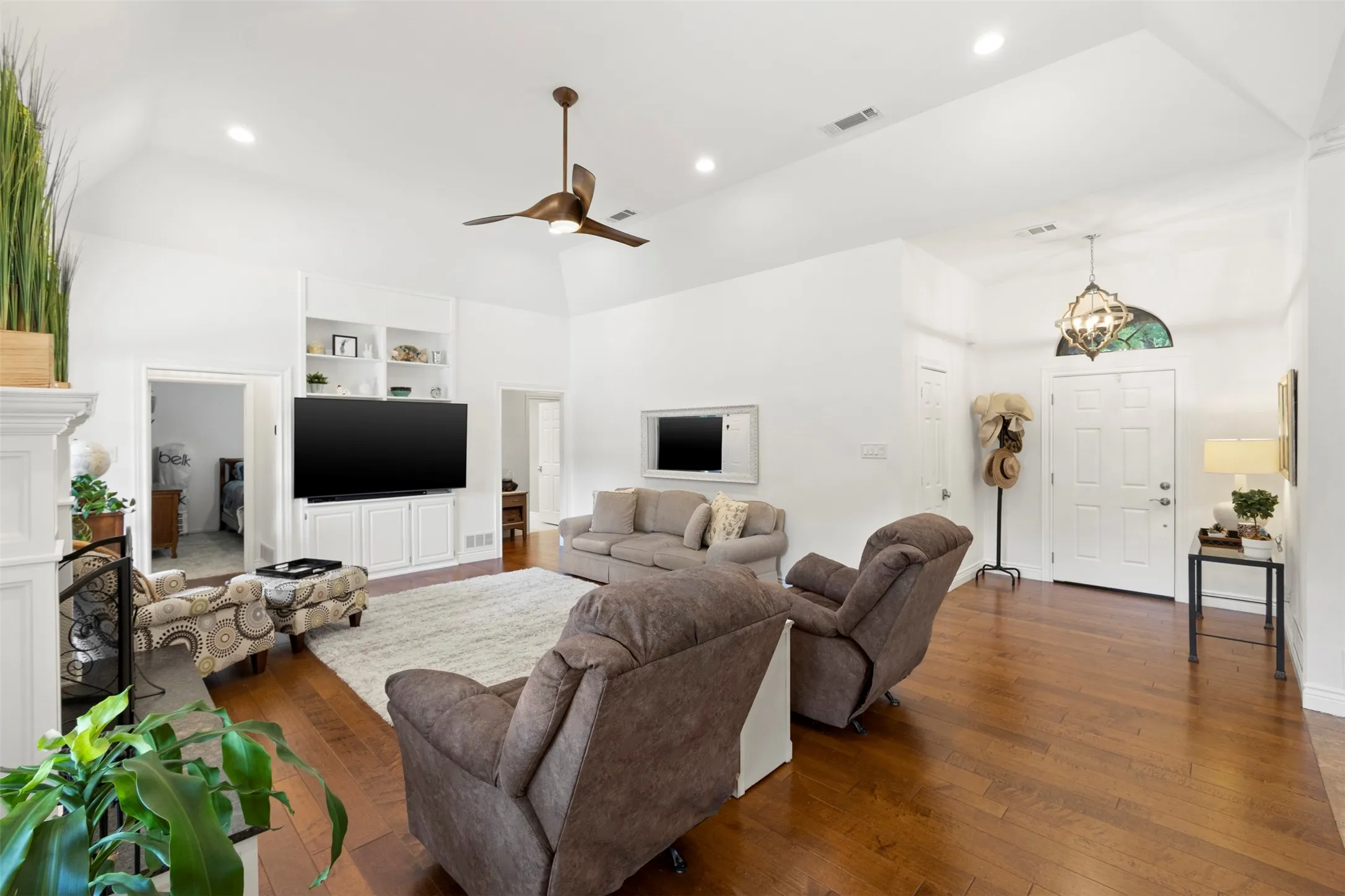 Vaulted ceilings, wood-finish flooring, built-in cabinetry with shelving, recessed lighting, and a prominent front entry with an overhead light fixture