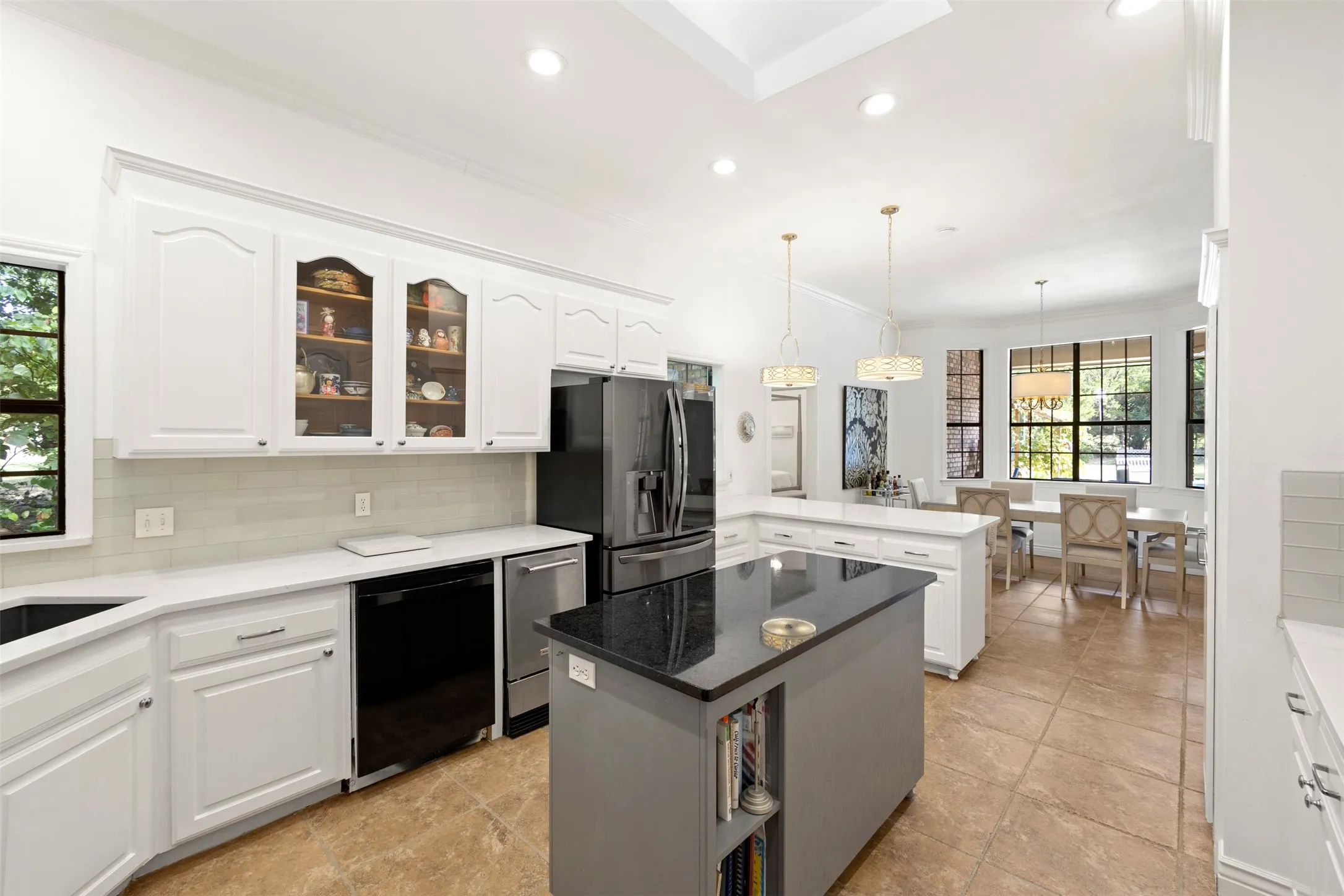 Kitchen featuring white cabinetry, a central island with a dark countertop, stainless steel appliances, and tile flooring