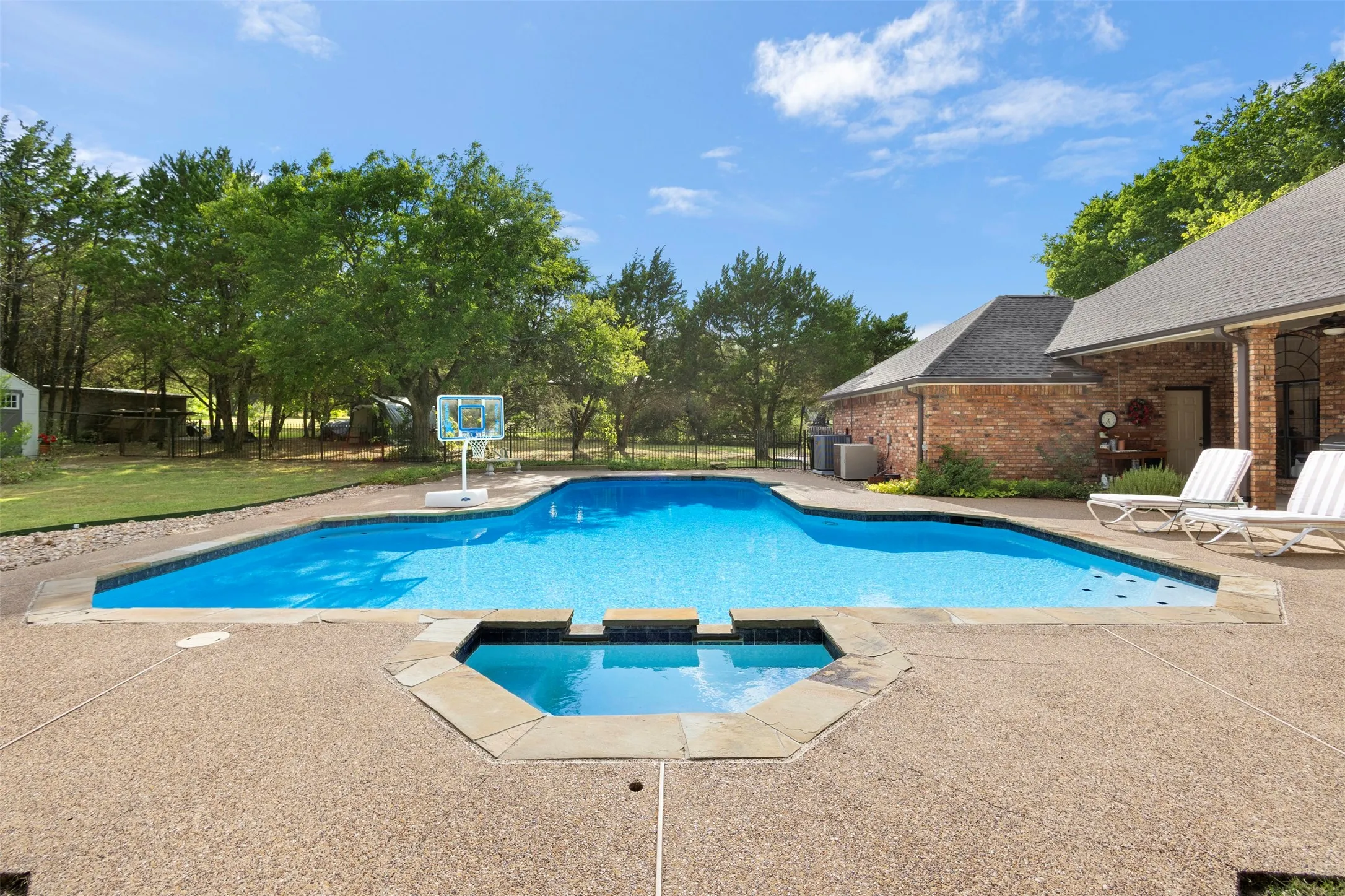Swimming pool with integrated spa, surrounded by an exposed aggregate concrete deck