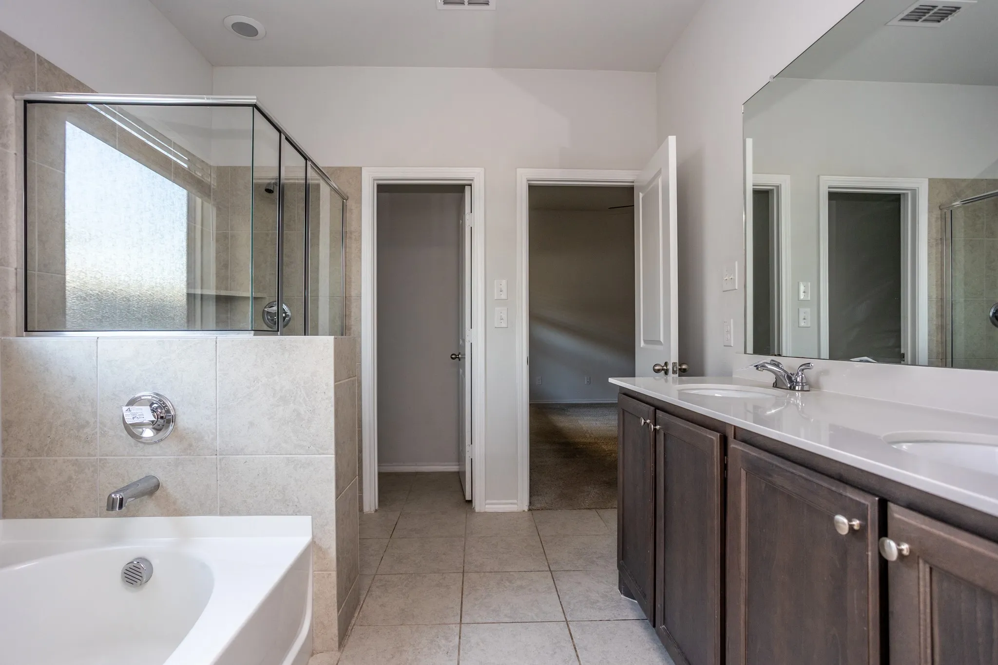 Dual vanity with white countertop, chrome fixtures, and dark wood-finish cabinetry