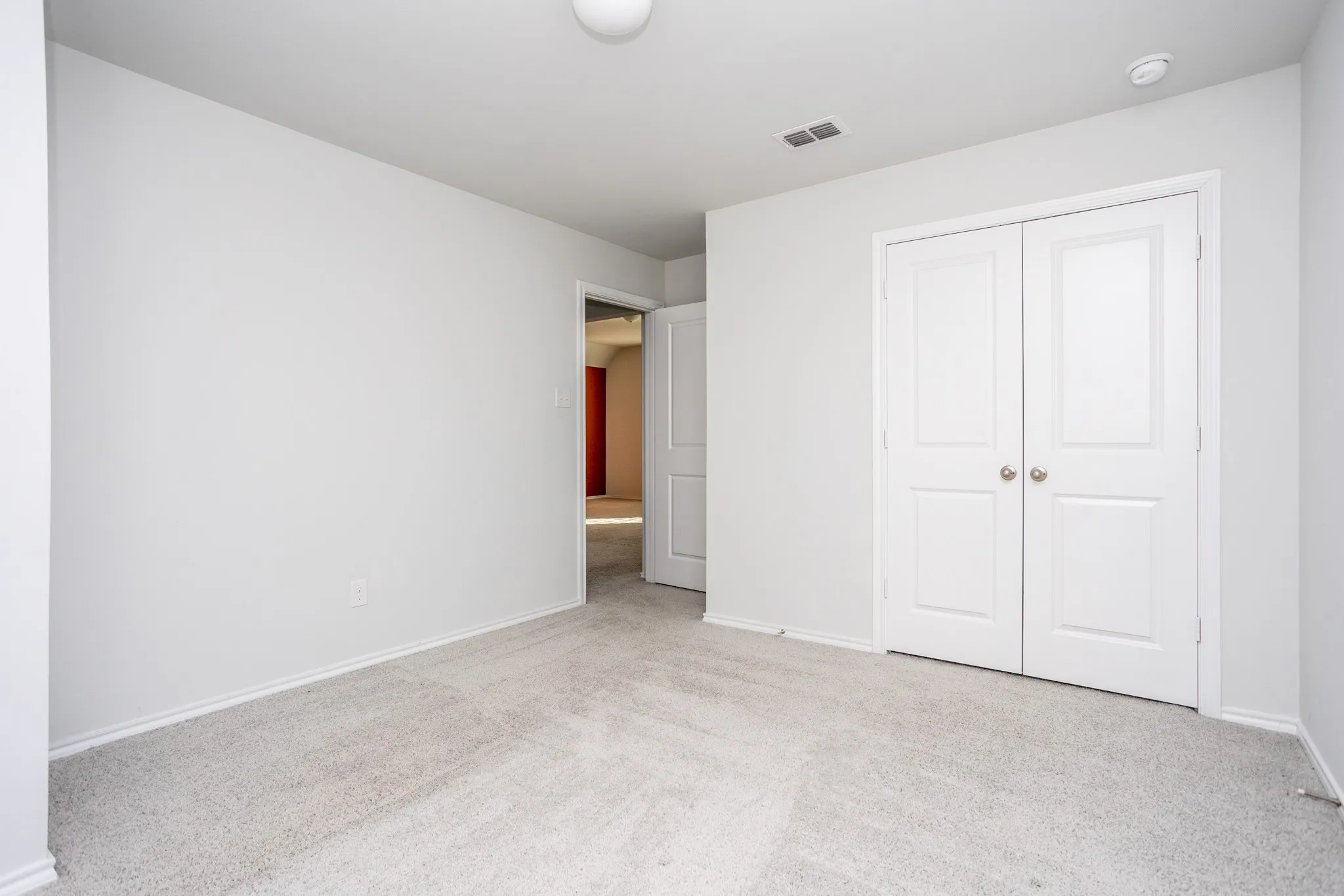 Neutral wall paint, light-toned carpet flooring, and white bi-fold closet doors