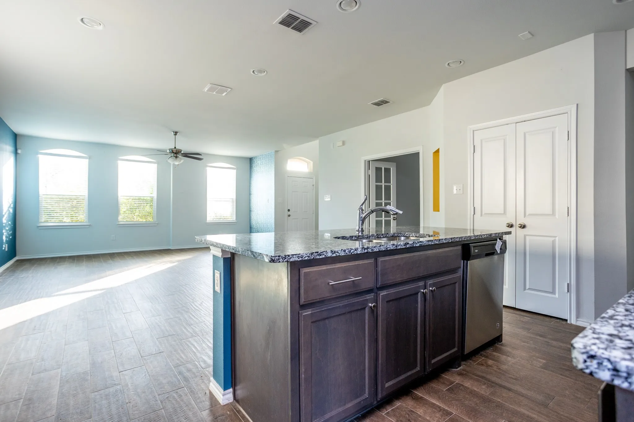 Kitchen island with granite countertop, integrated sink, and stainless steel dishwasher