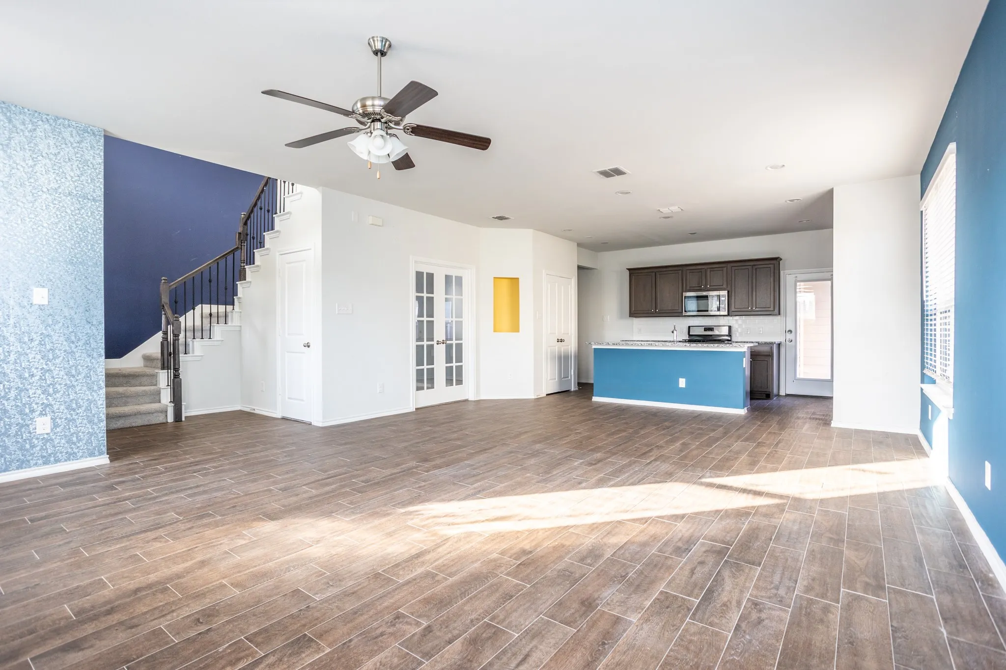 Open-concept living space featuring wood-finish flooring, a contemporary ceiling fan, and a kitchen island with built-in cabinetry
