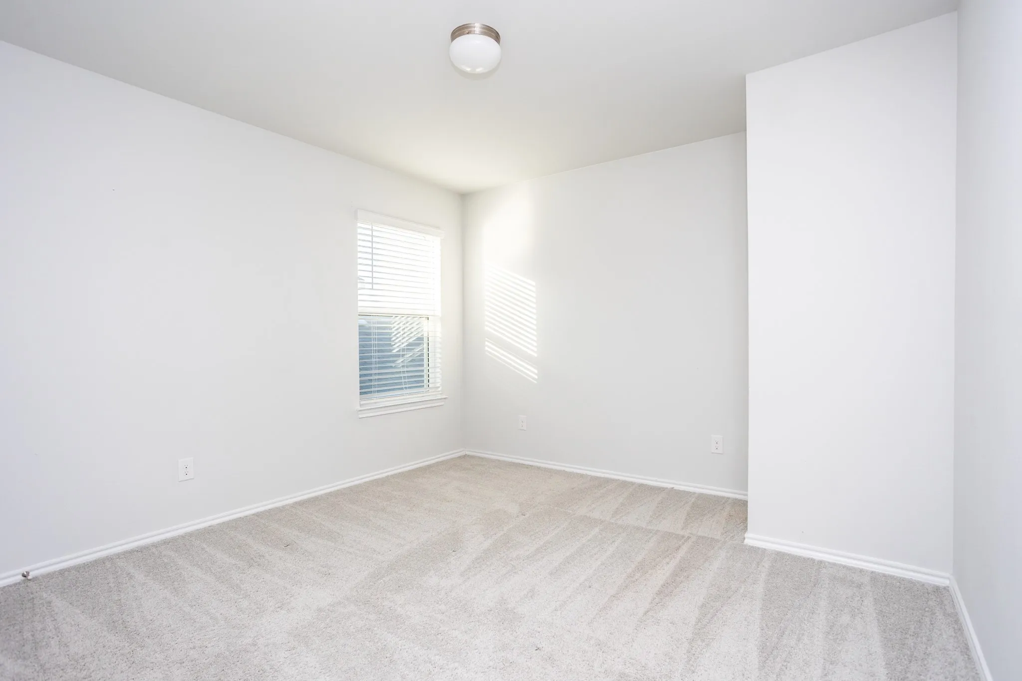 Neutral wall finishes with a window featuring horizontal blinds
