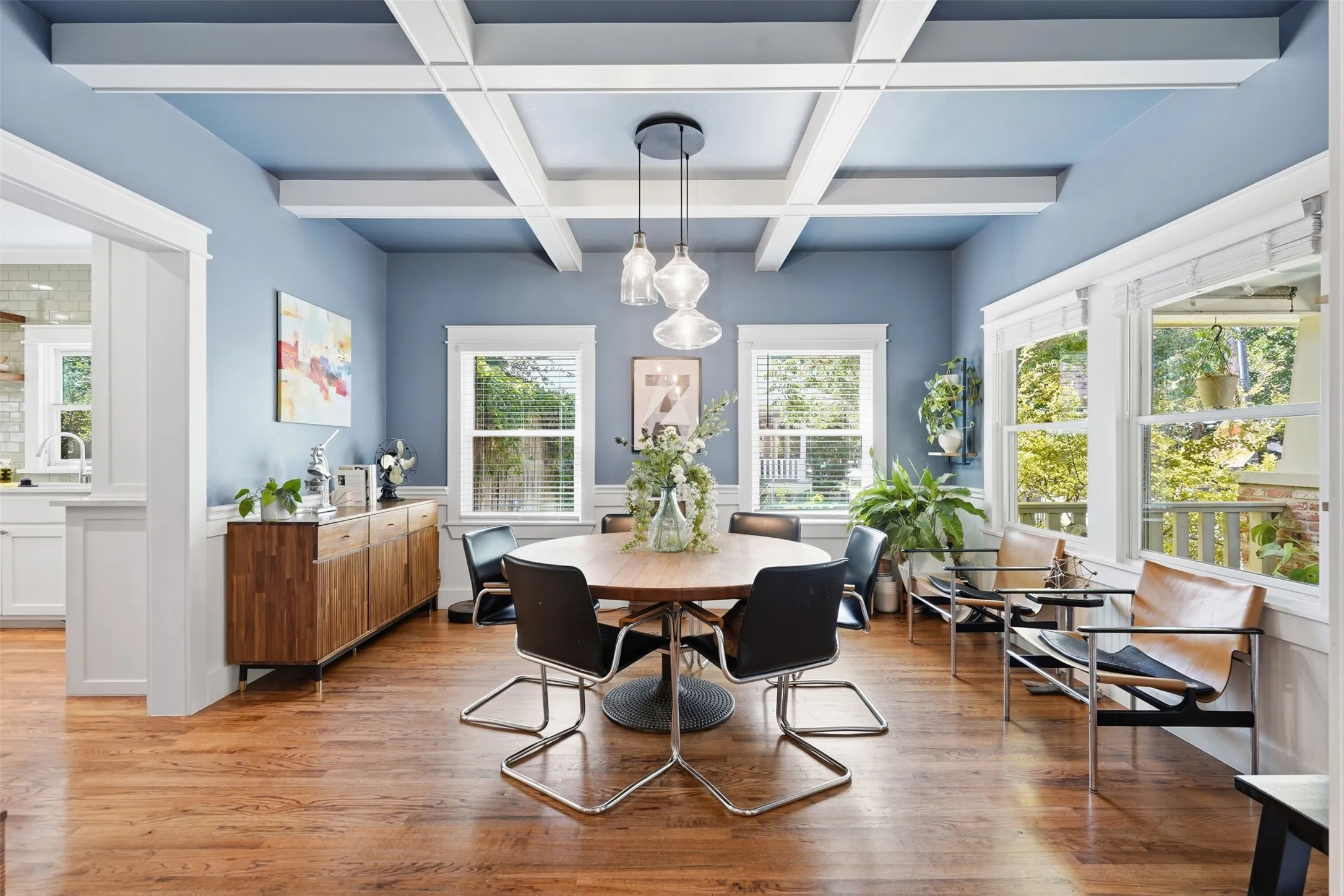 Hardwood flooring, coffered ceiling, pendant lighting, multiple windows, and white trim