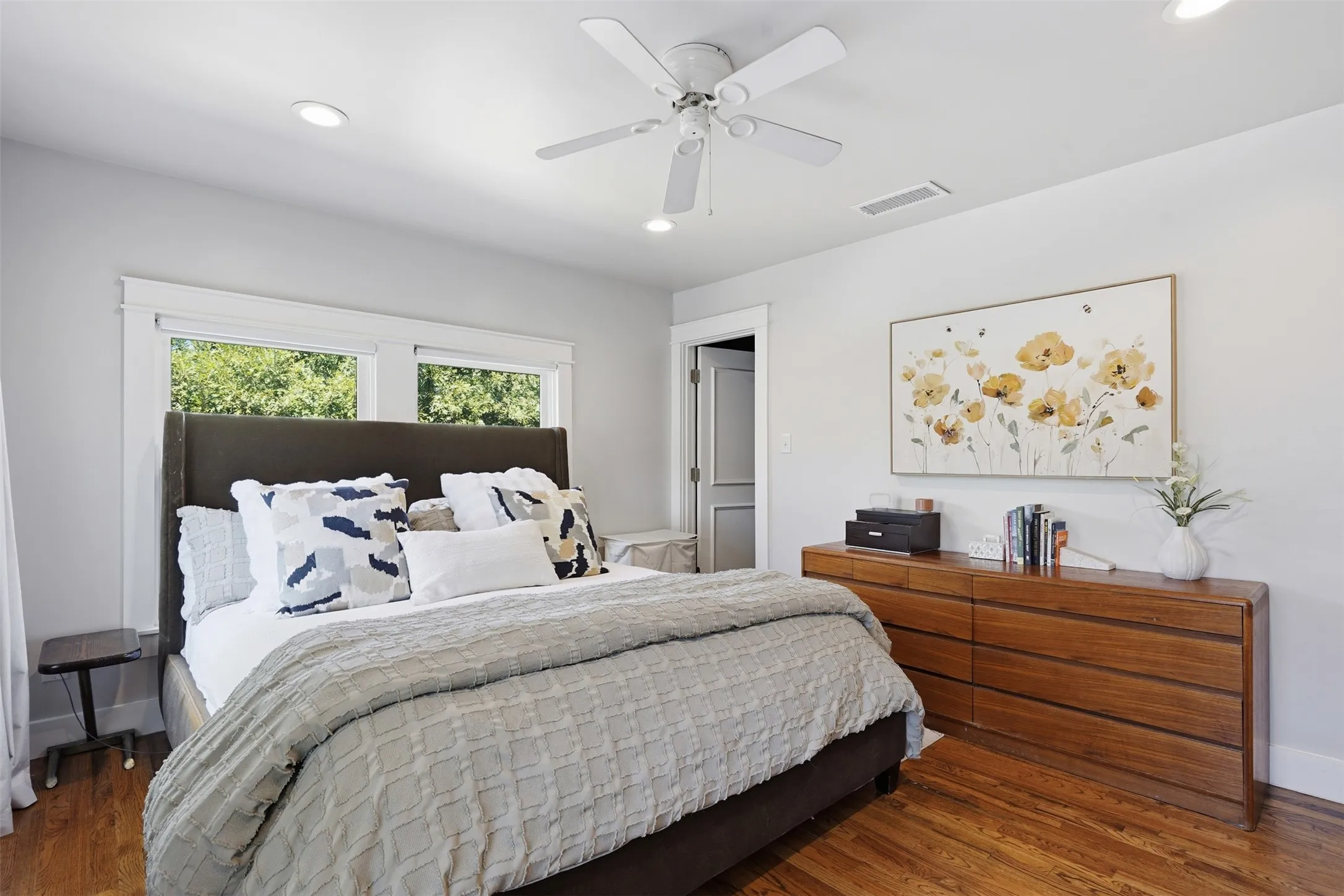 Hardwood flooring complemented by recessed lighting and a ceiling fan