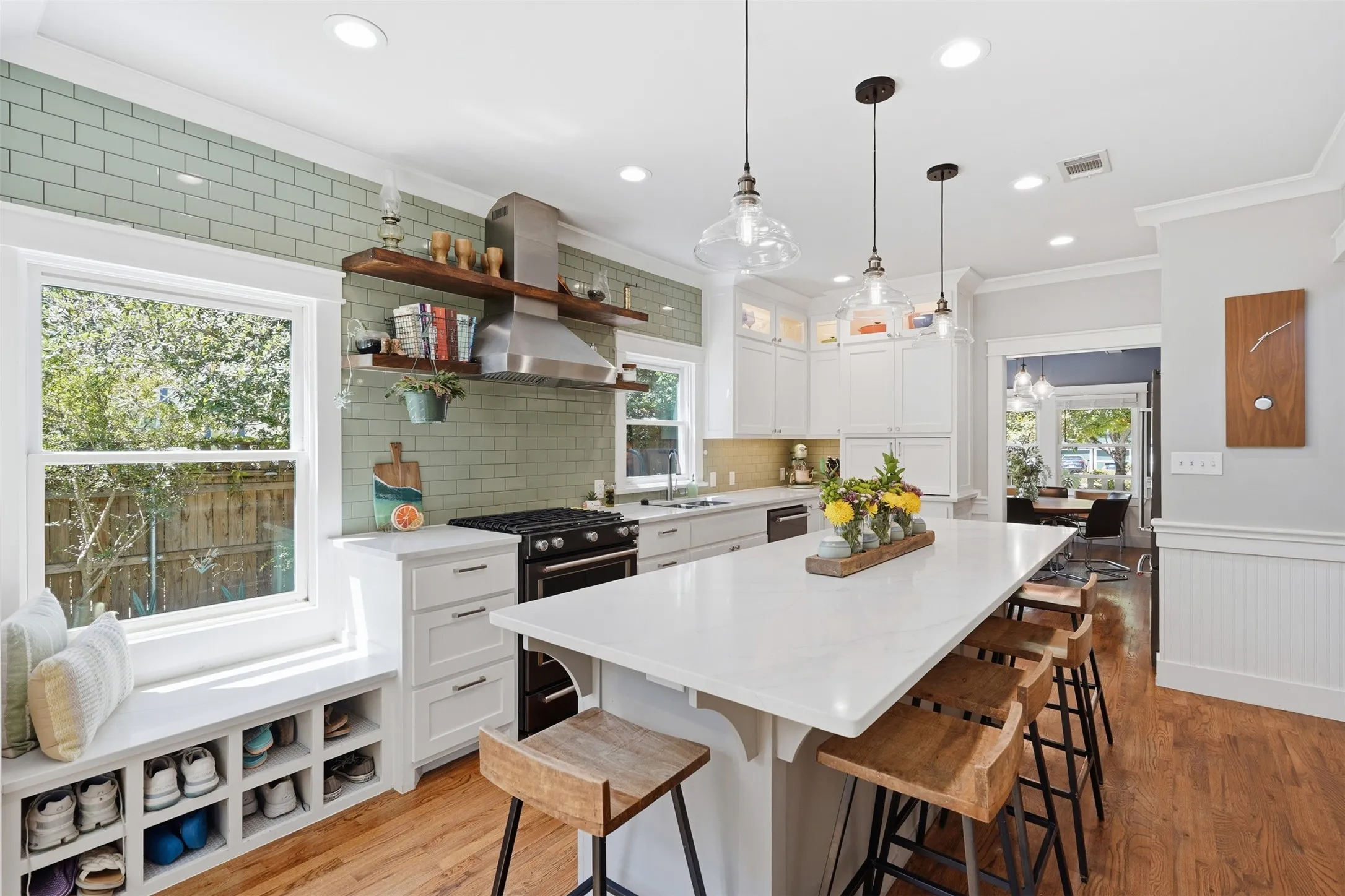 Spacious kitchen featuring an expansive central island, subway tile backsplash, stainless steel range hood, white cabinetry, and recessed lighting