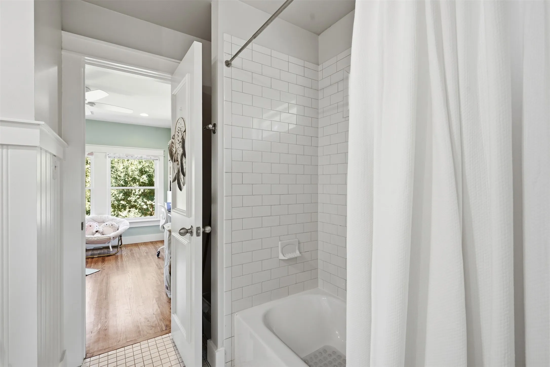 Bathroom featuring a subway tile shower surround, a white bathtub, and wainscoting
