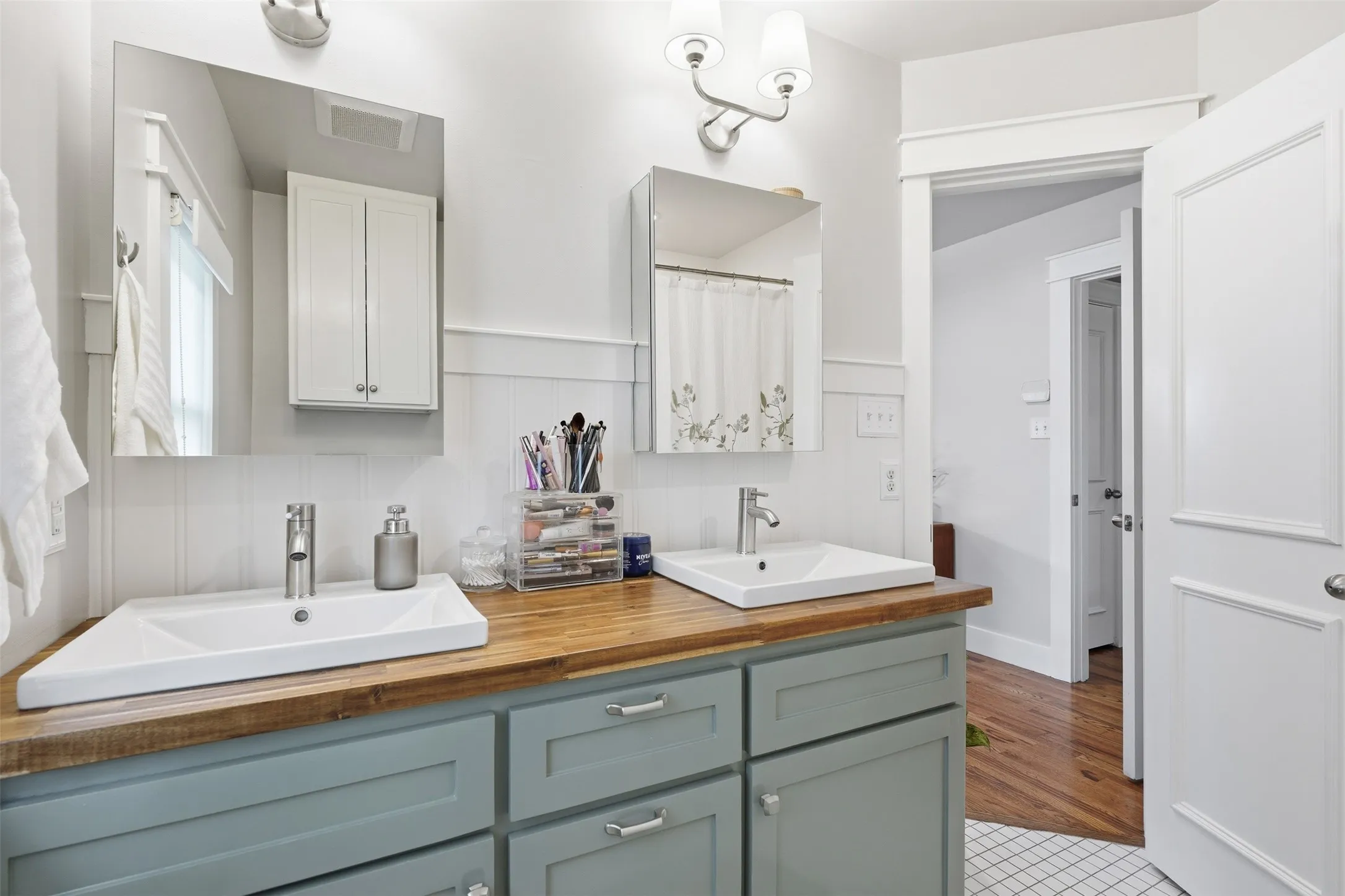 Dual vanity with wood-finish countertop, undermount sinks, and painted cabinetry