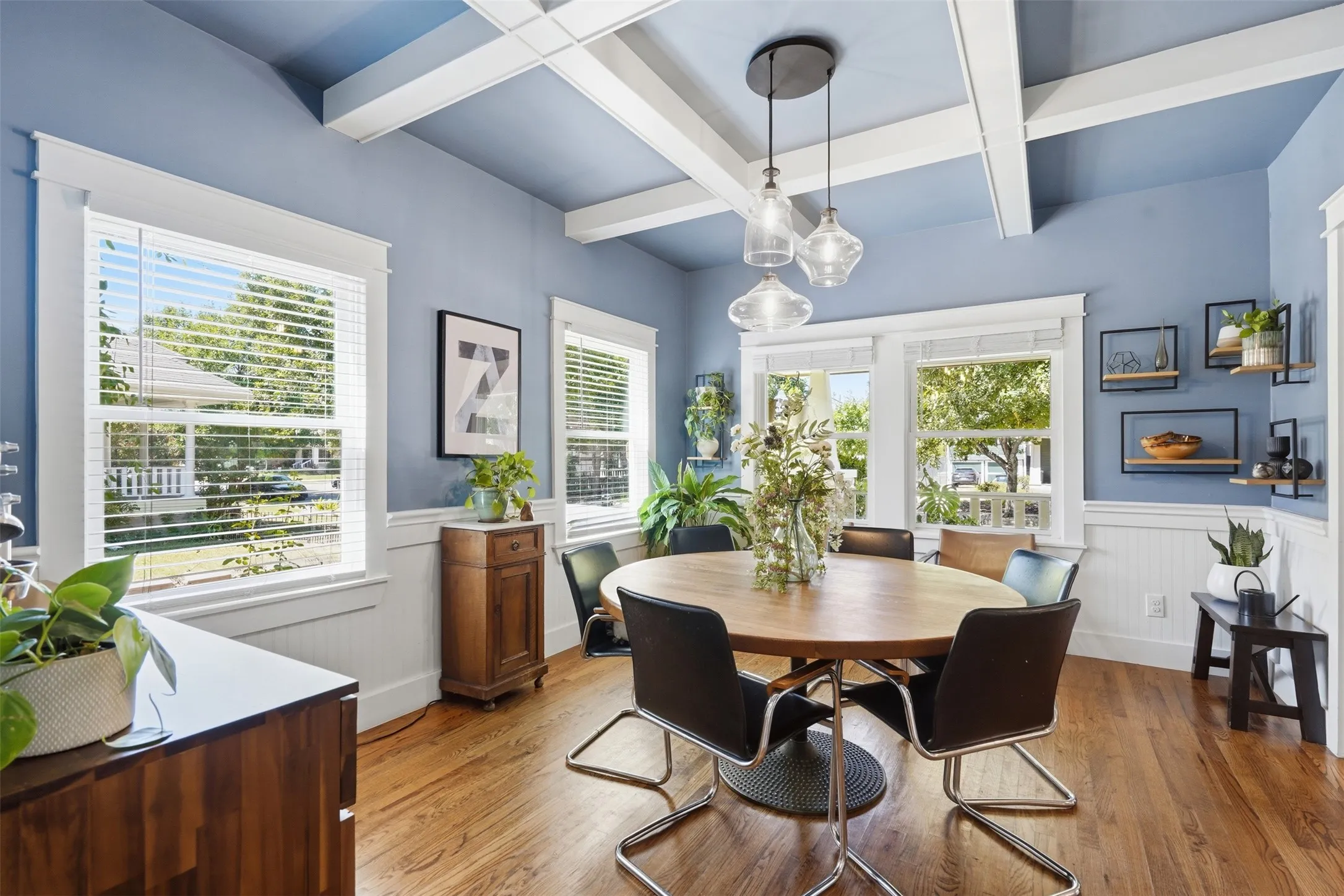 Hardwood flooring, coffered ceiling, wainscoting, multiple windows, and pendant lighting