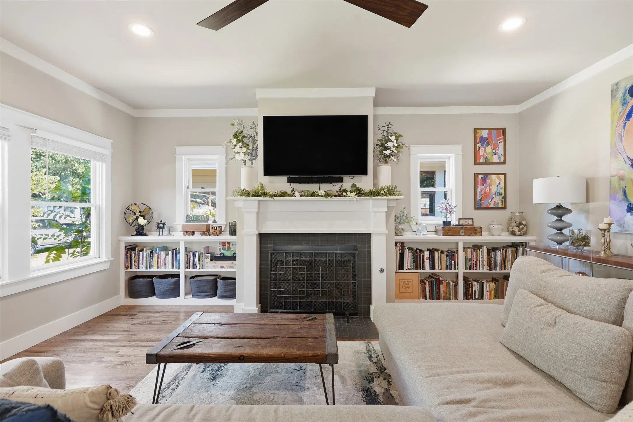 Fireplace with white mantel, built-in shelving, wood-finish flooring, recessed lighting, and a ceiling fan
