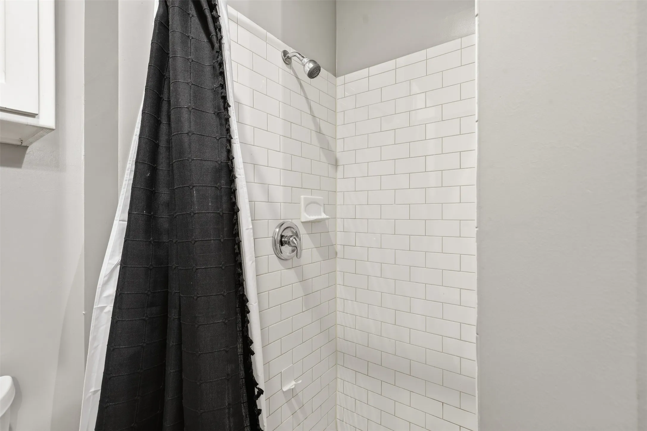 White subway tile shower surround with chrome fixtures