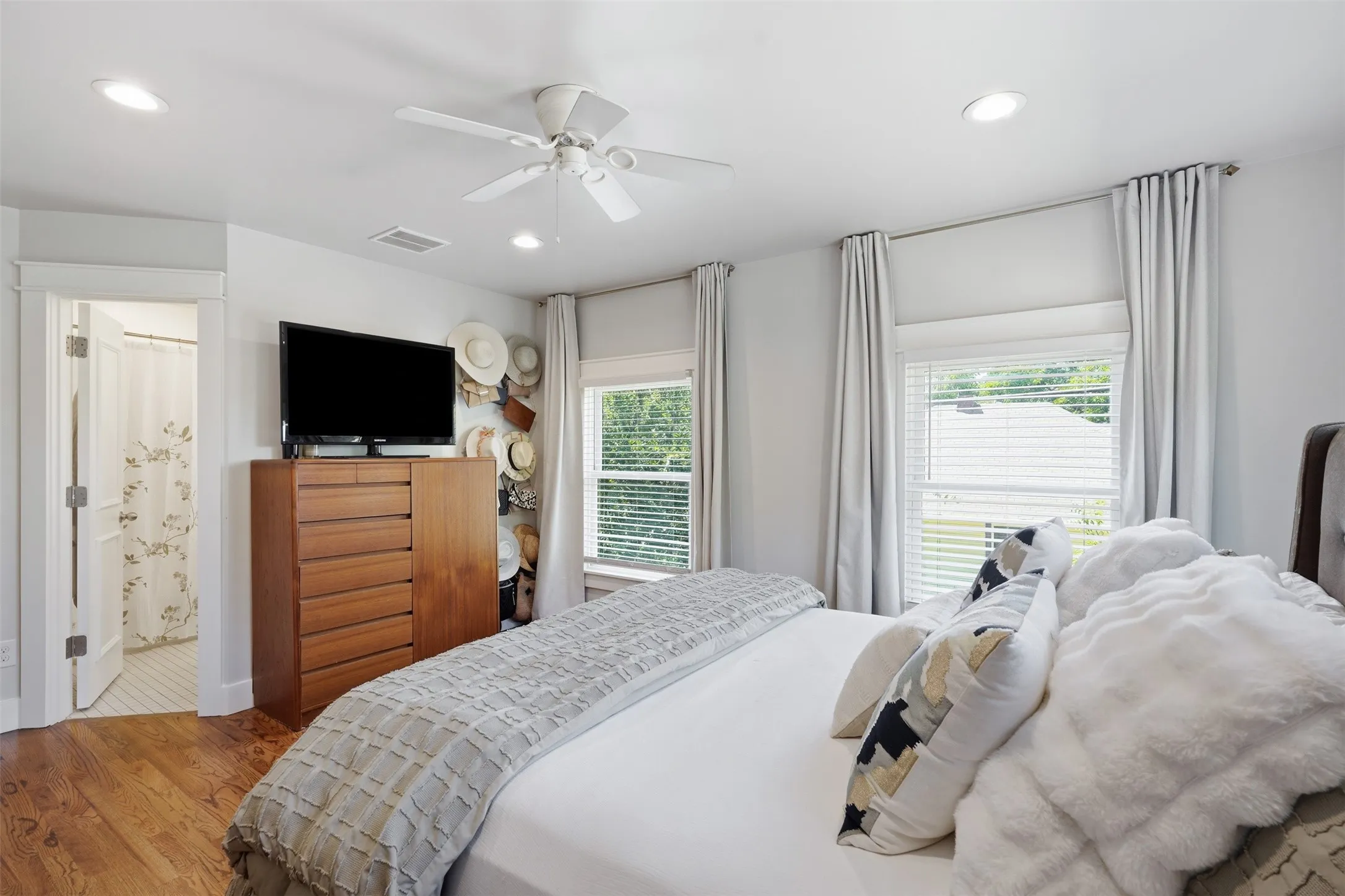 Recessed lighting, ceiling fan, wood-finish flooring, white window blinds, and an attached bathroom with tiled flooring