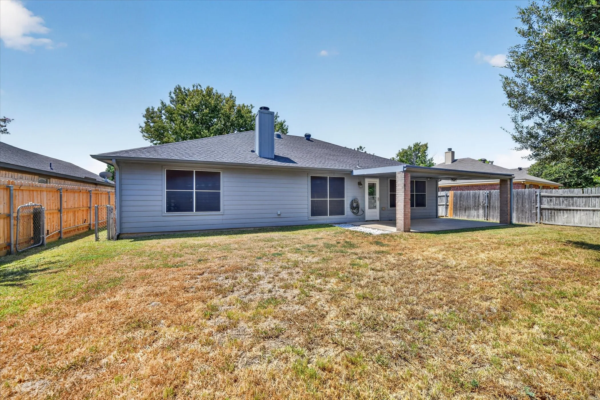 Expansive backyard featuring a covered patio, composite shingle roof, and durable siding