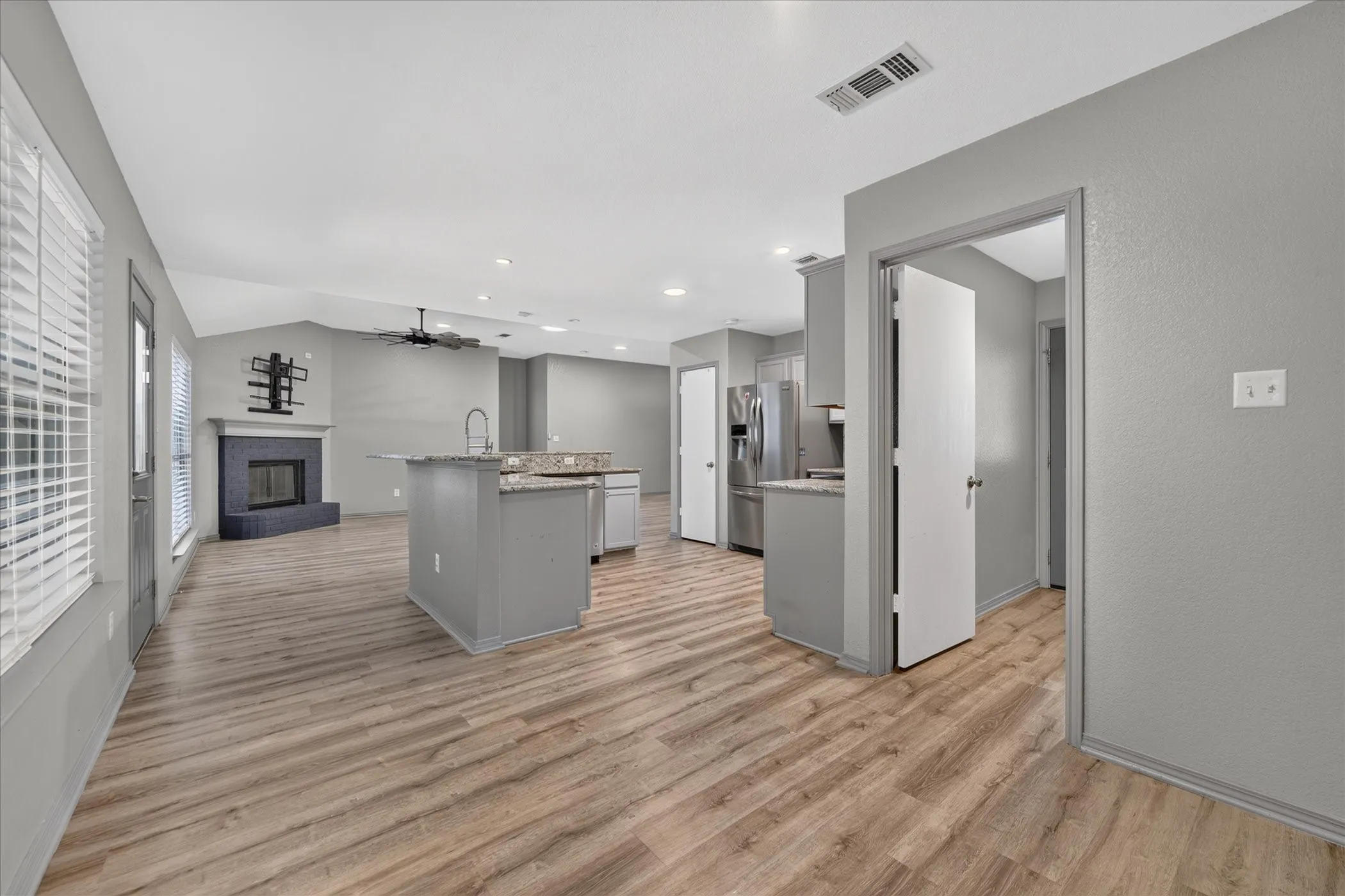 Open-concept living area featuring wood-finish flooring, a contemporary fireplace, and vaulted ceilings