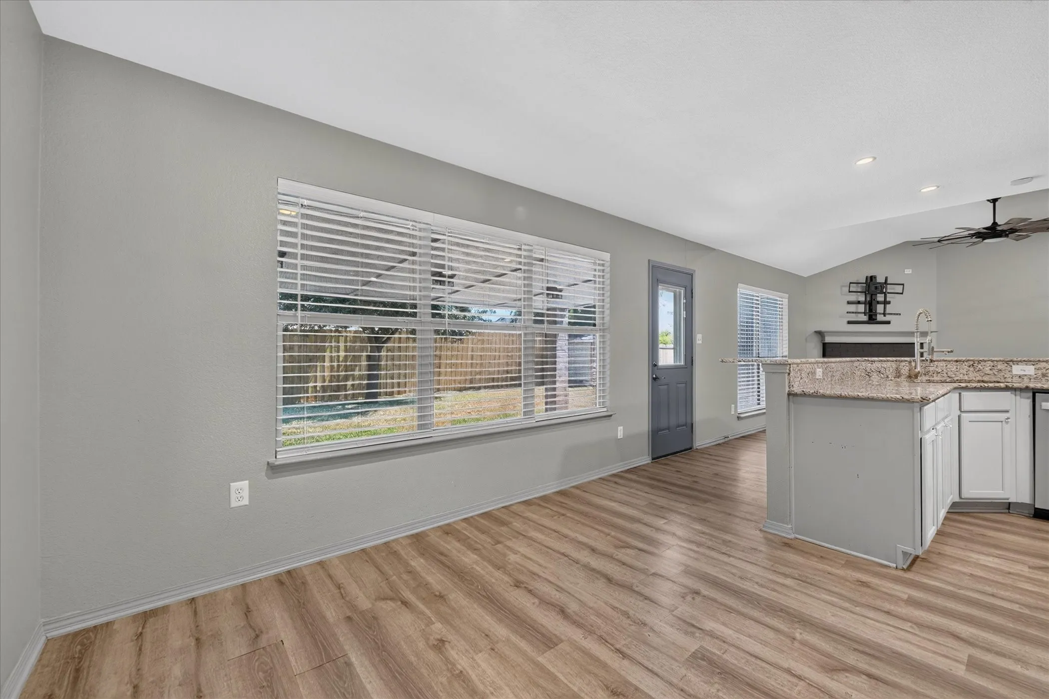 Wood-finish flooring throughout, light gray wall paint, and multiple windows with blinds