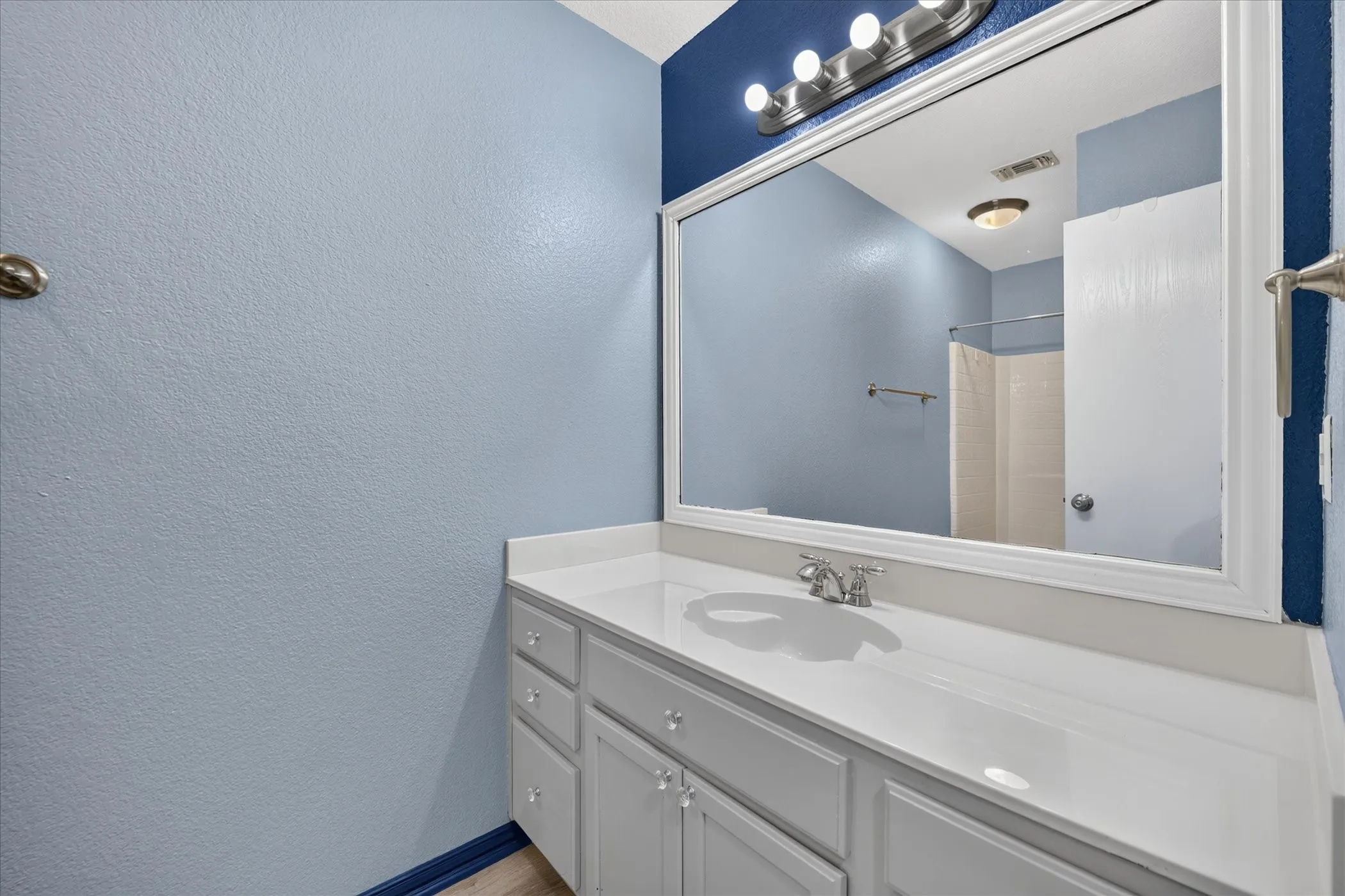 White vanity with dual cabinet doors and three drawers, integrated single basin sink, and chrome-finish faucet