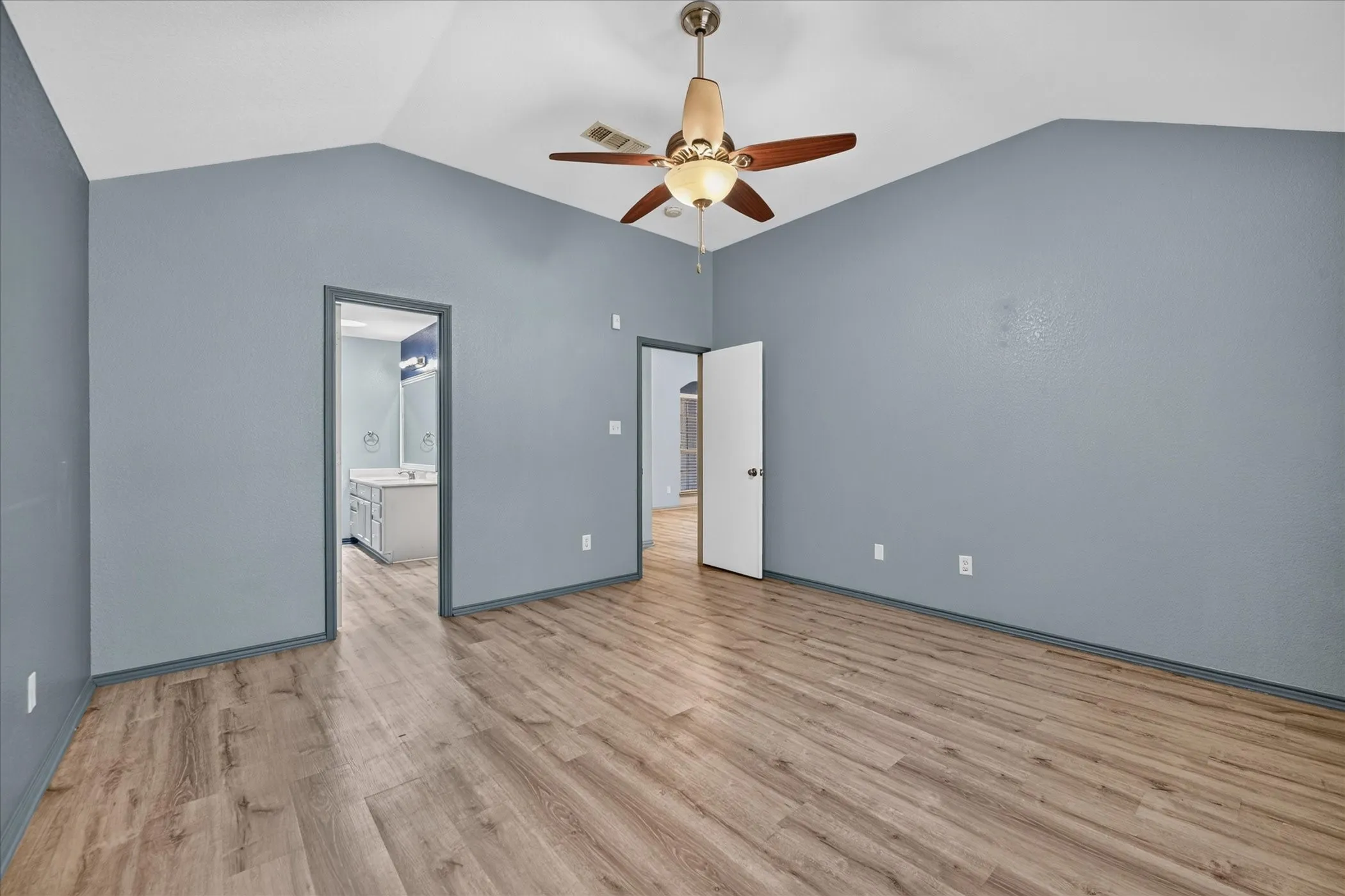 Vaulted ceiling with a ceiling fan, wood-finish flooring, and gray wall paint