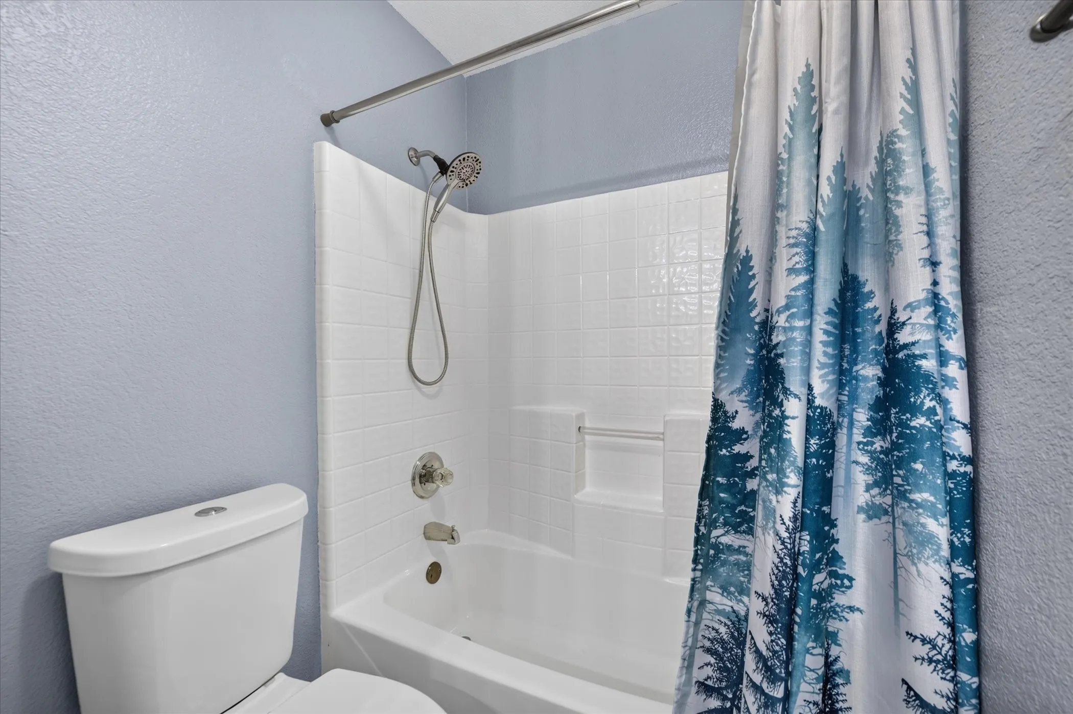 Bathtub with an integrated shower, white subway tile surround, and a chrome shower head with a handheld attachment