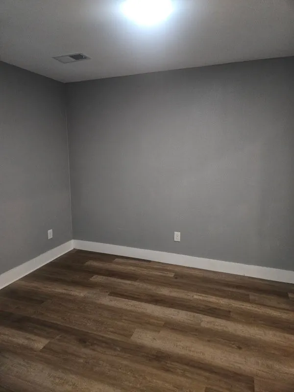 Bedroom. Wood-finish flooring with white trim and neutral wall tones