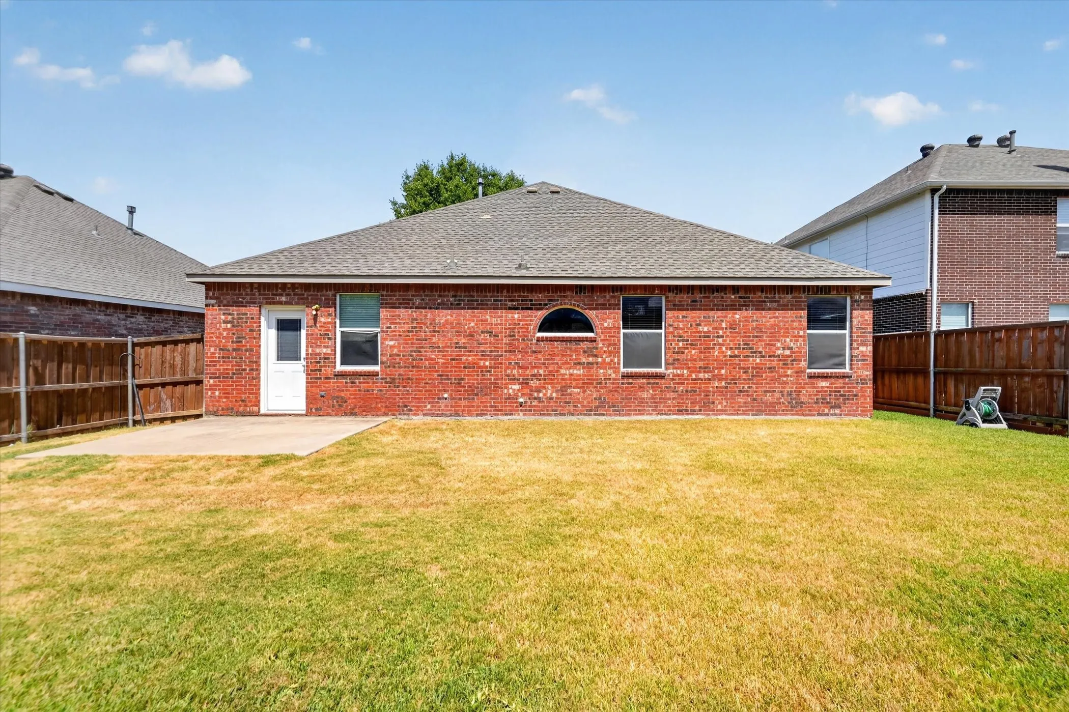 Expansive backyard with a large grass lawn, privacy fencing, and a concrete patio