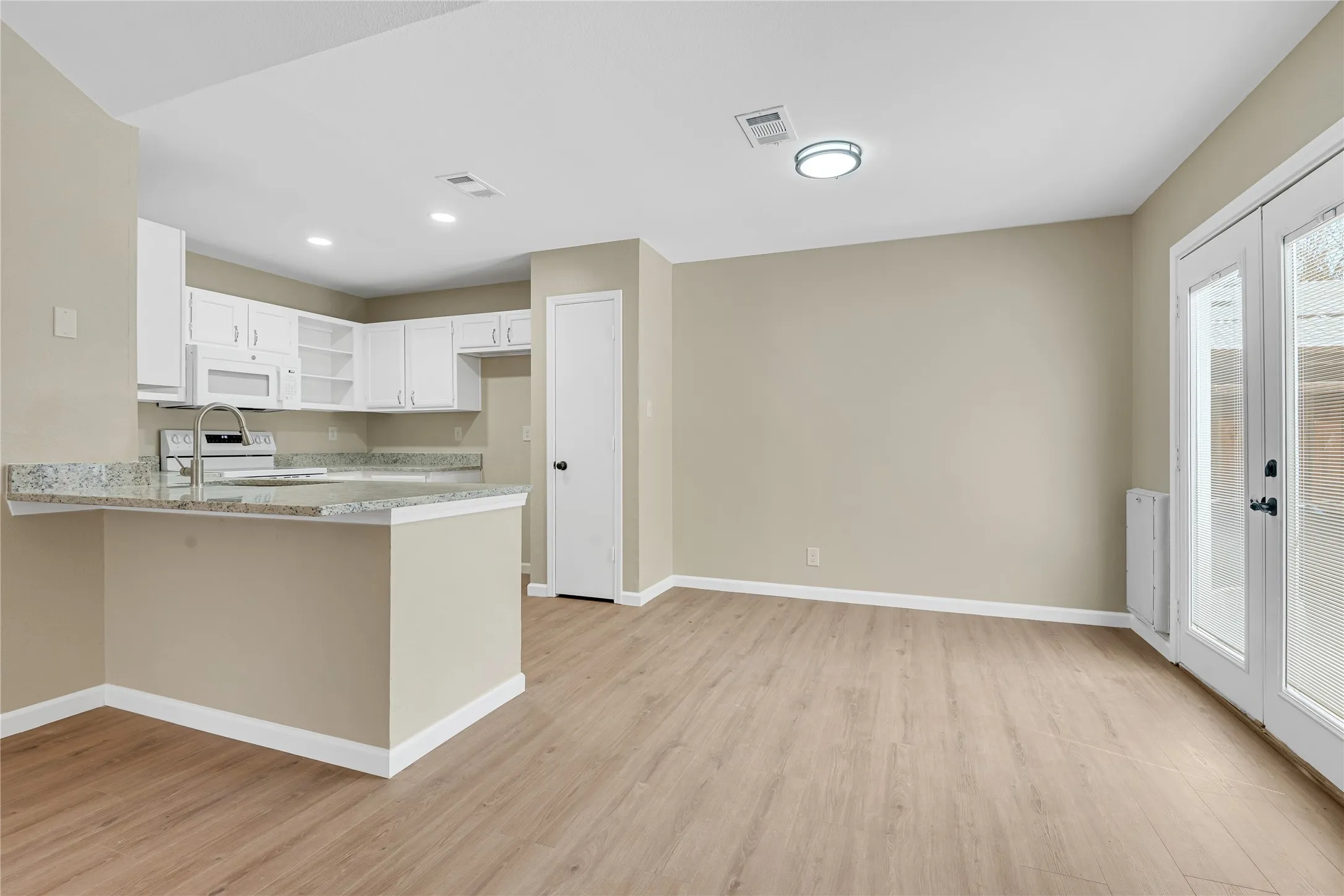 Kitchen with white cabinetry, stainless steel sink, and light-toned countertops