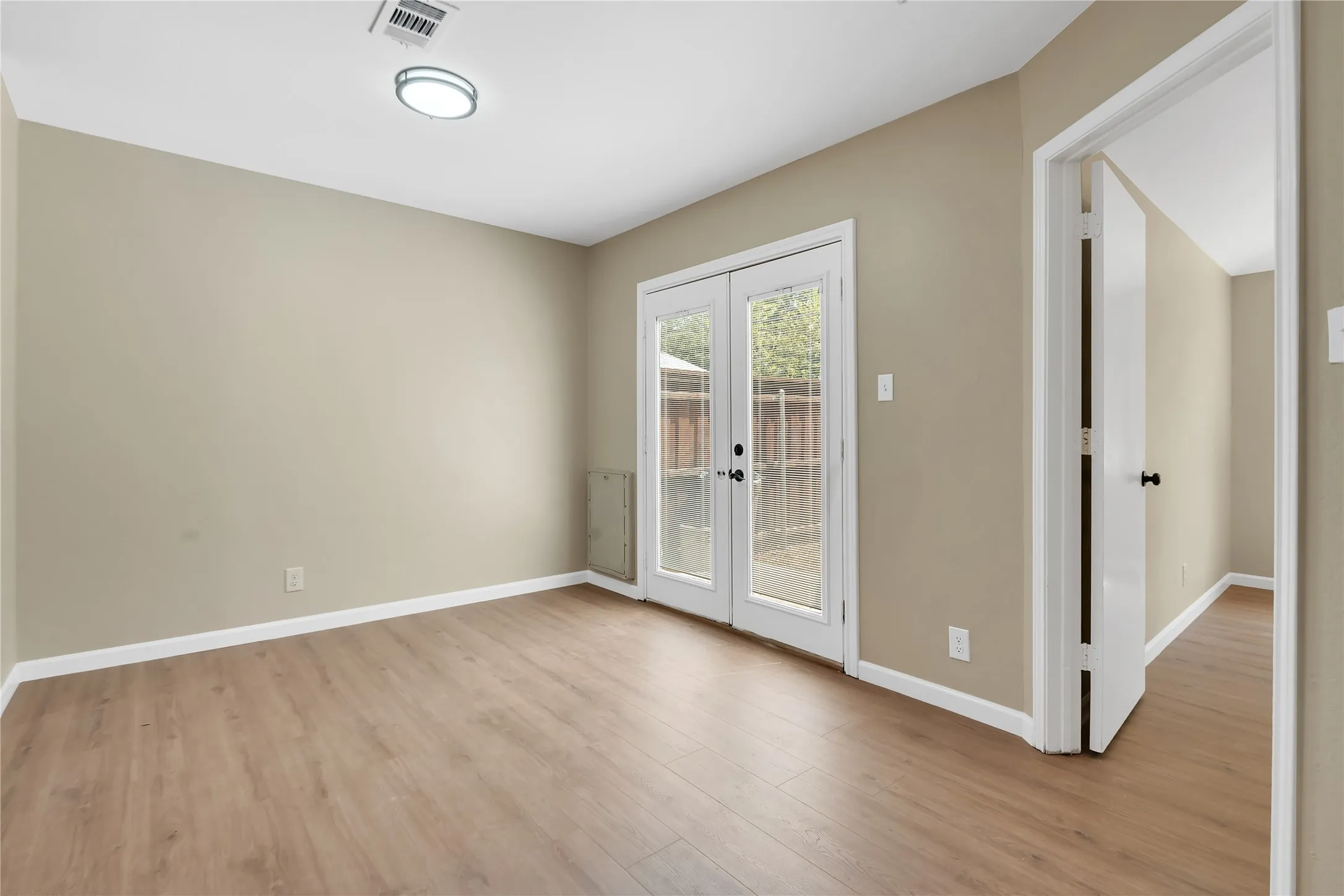Wood-finish flooring, neutral wall tones, white trim, and a flush-mount ceiling light fixture