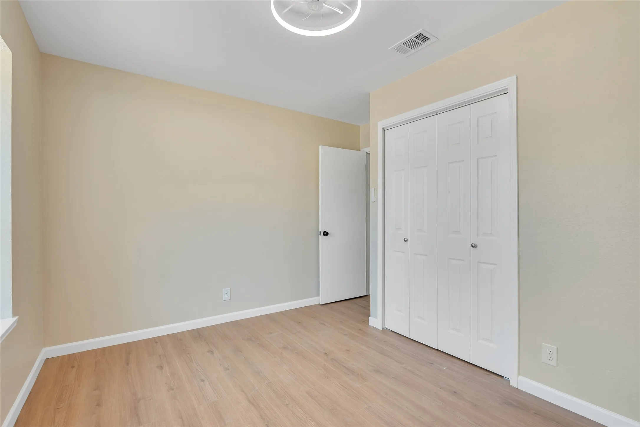 Wood-finish flooring, neutral wall tones, white bi-fold closet doors, and recessed lighting