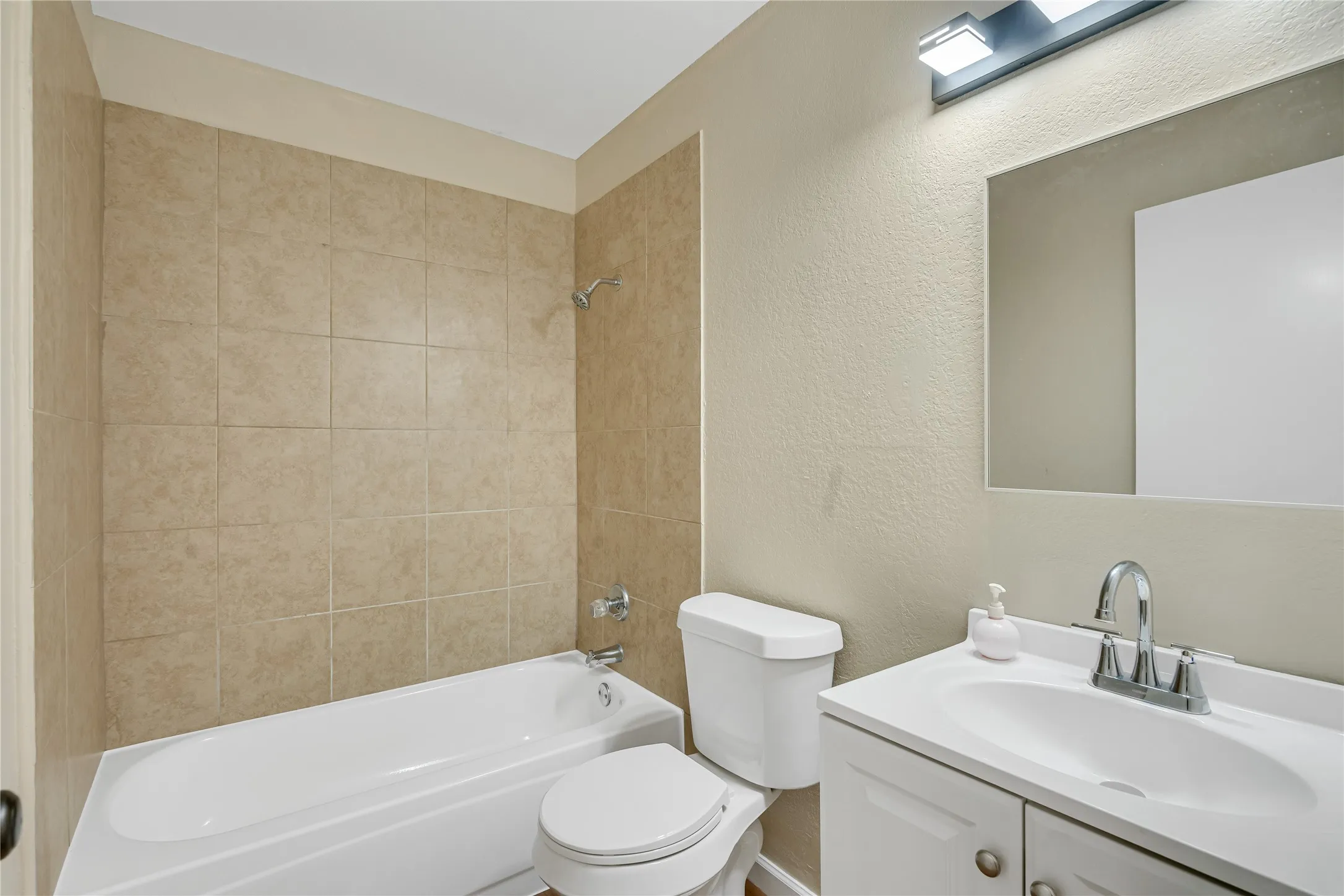 White vanity with integrated sink and chrome faucet, rectangular mirror, and a white toilet