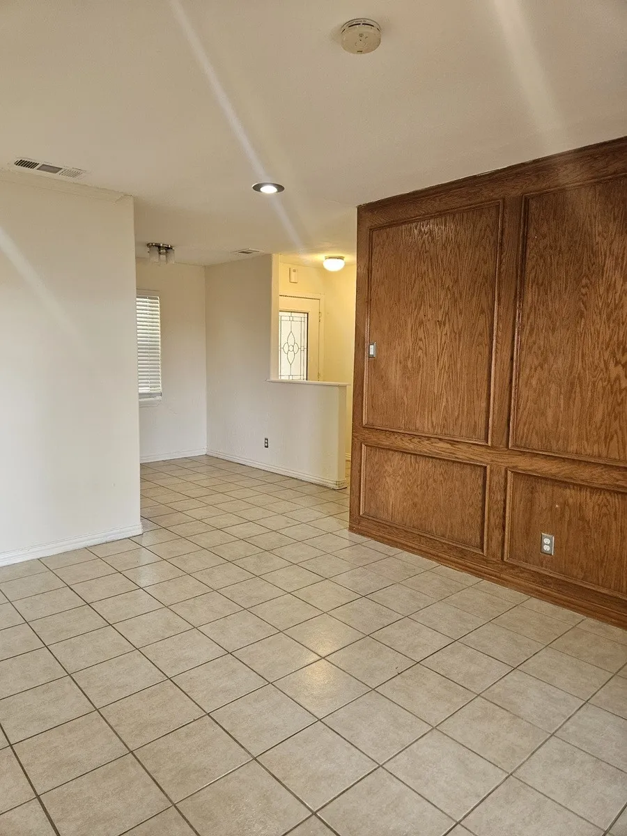 Wood-paneled accent wall, tile flooring, recessed lighting, and a transom window with decorative glass