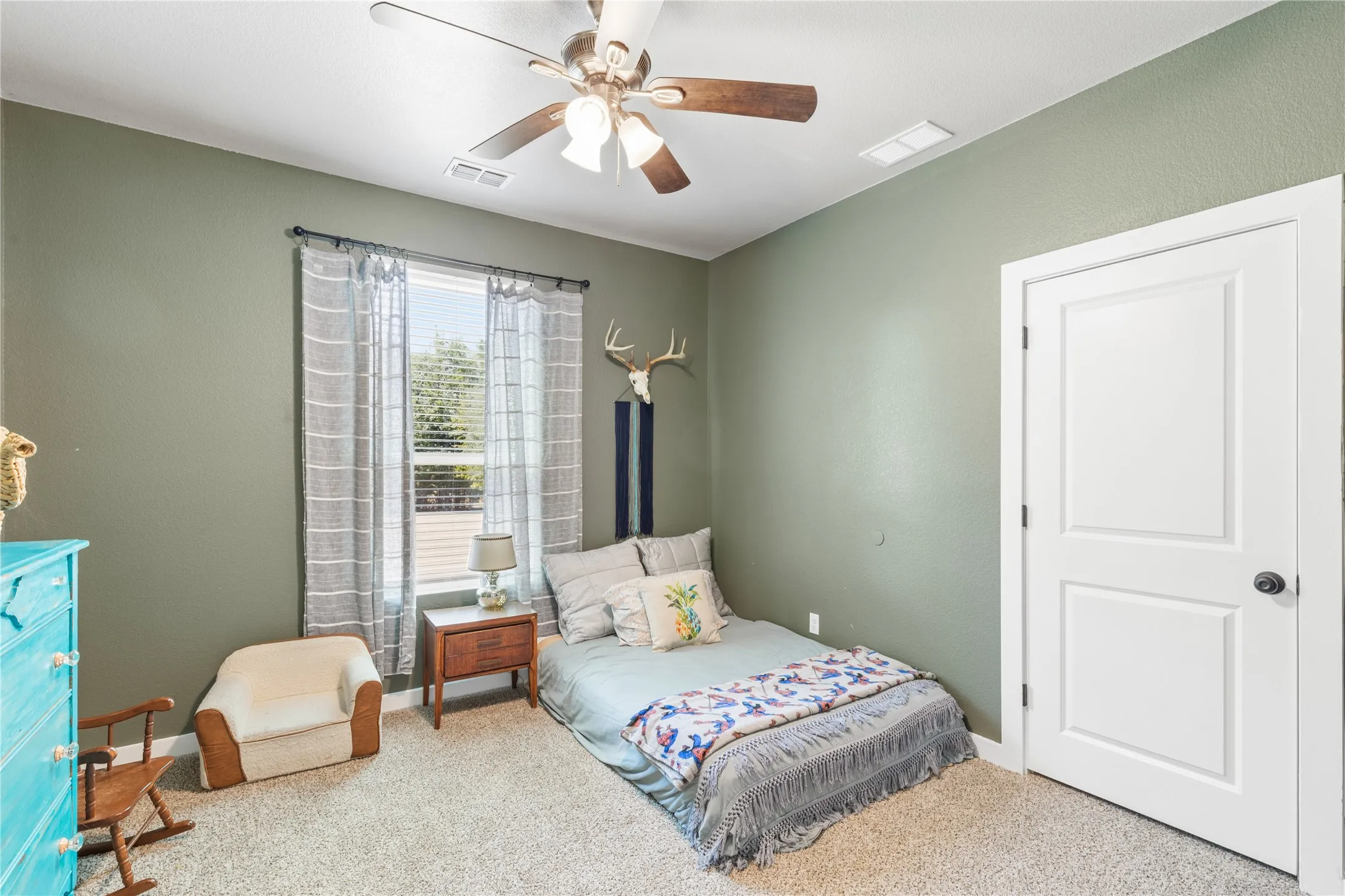 Textured wall finish, ceiling fan with integrated lighting, paneled interior door, window with blinds, and carpeted flooring