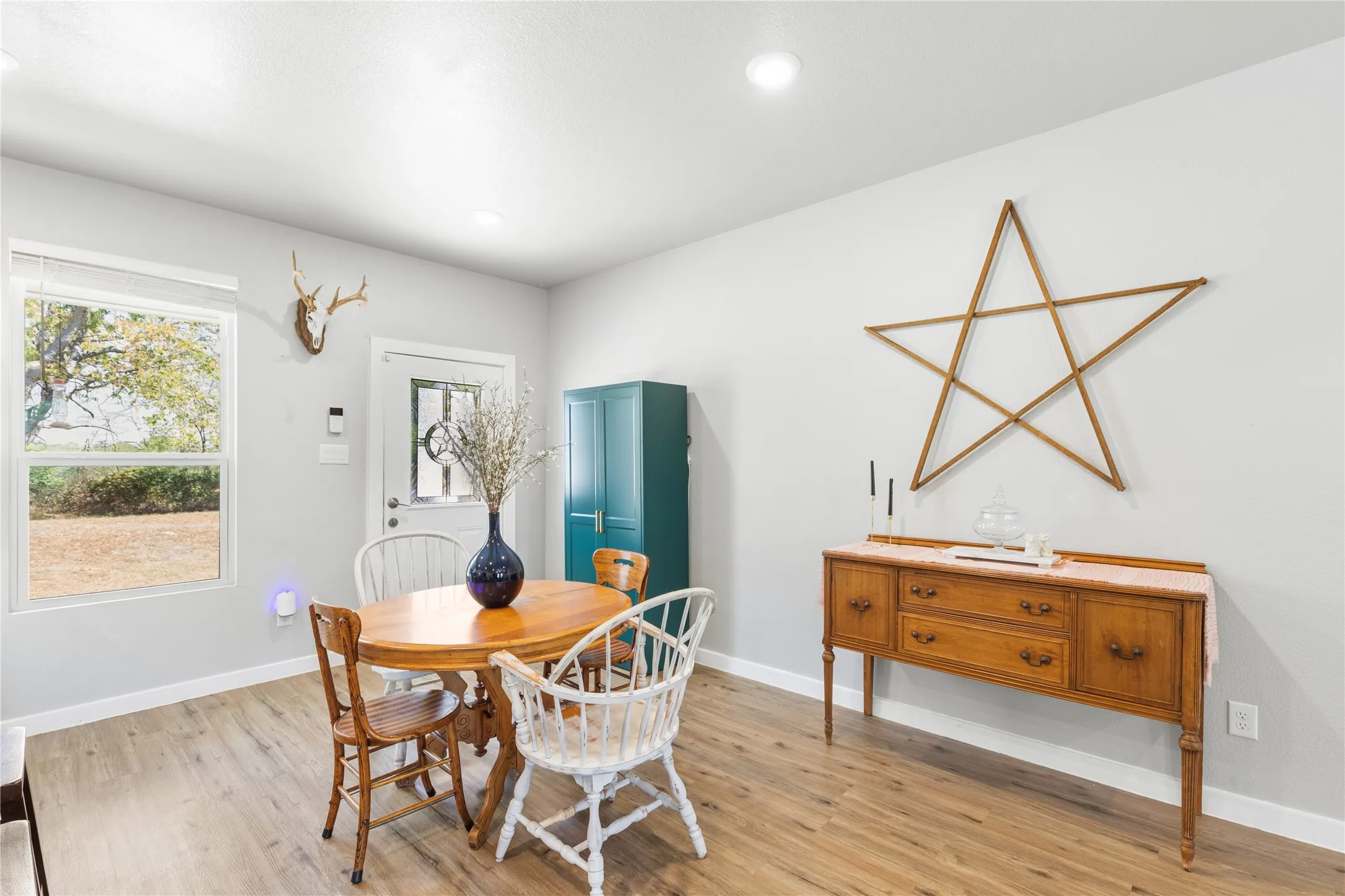 Recessed lighting, wood-finish flooring, white walls, white window blinds, and a white paneled door with decorative glass inserts