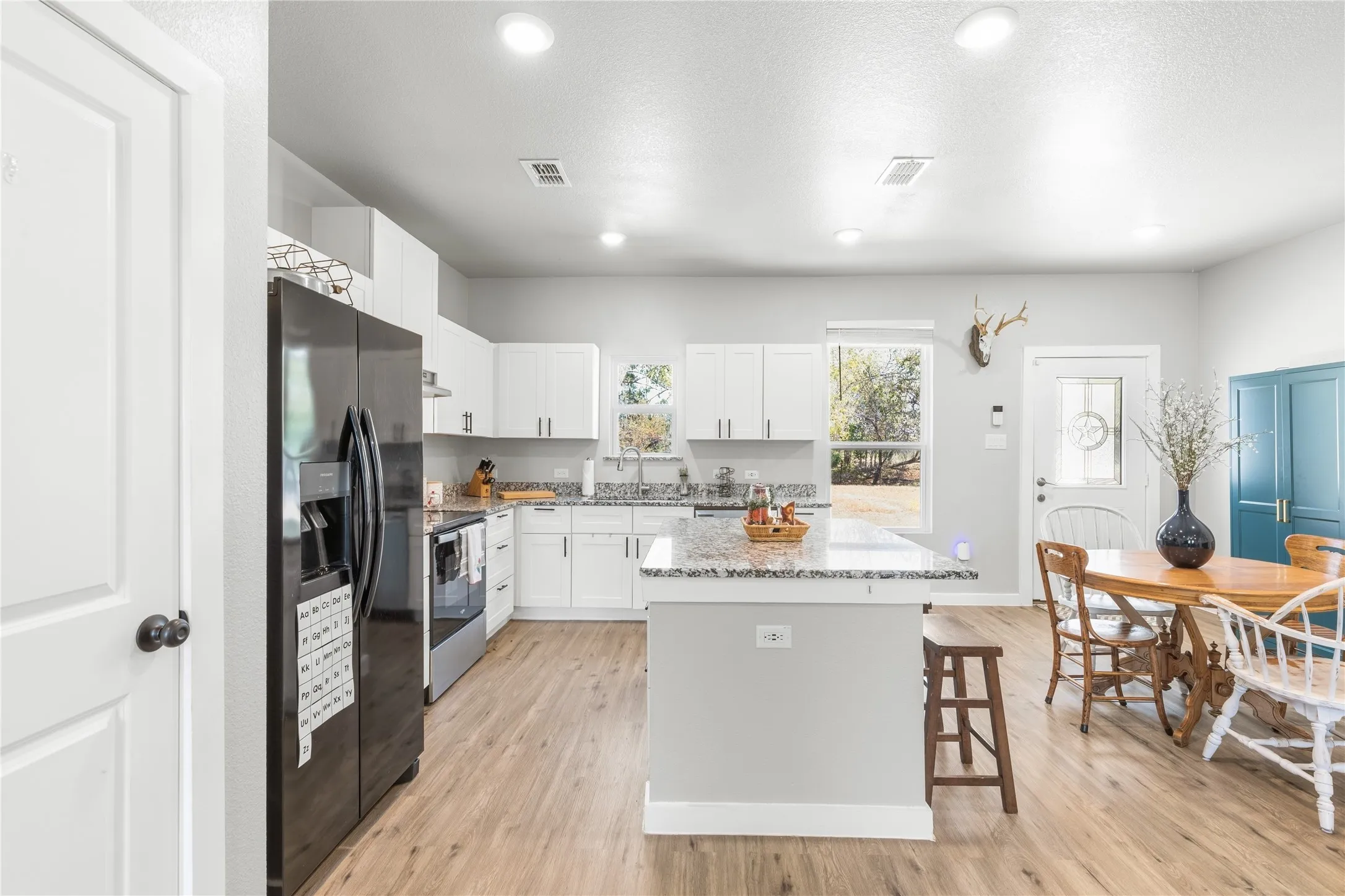 Kitchen featuring white cabinetry, a central island with a stone-finish countertop, wood-finish flooring, and recessed lighting