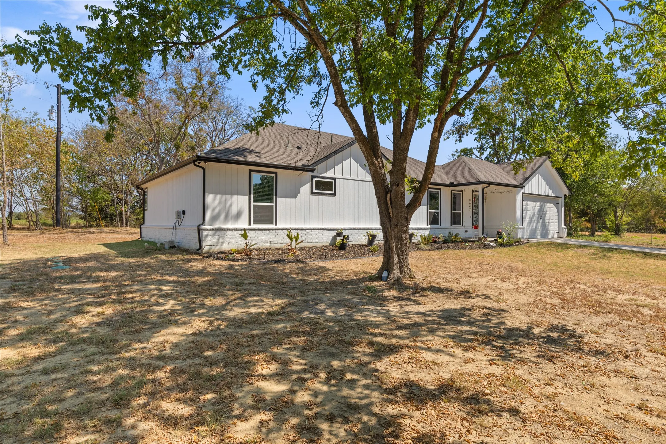 Single-story residence featuring white siding, dark-trimmed windows, and a two-car garage