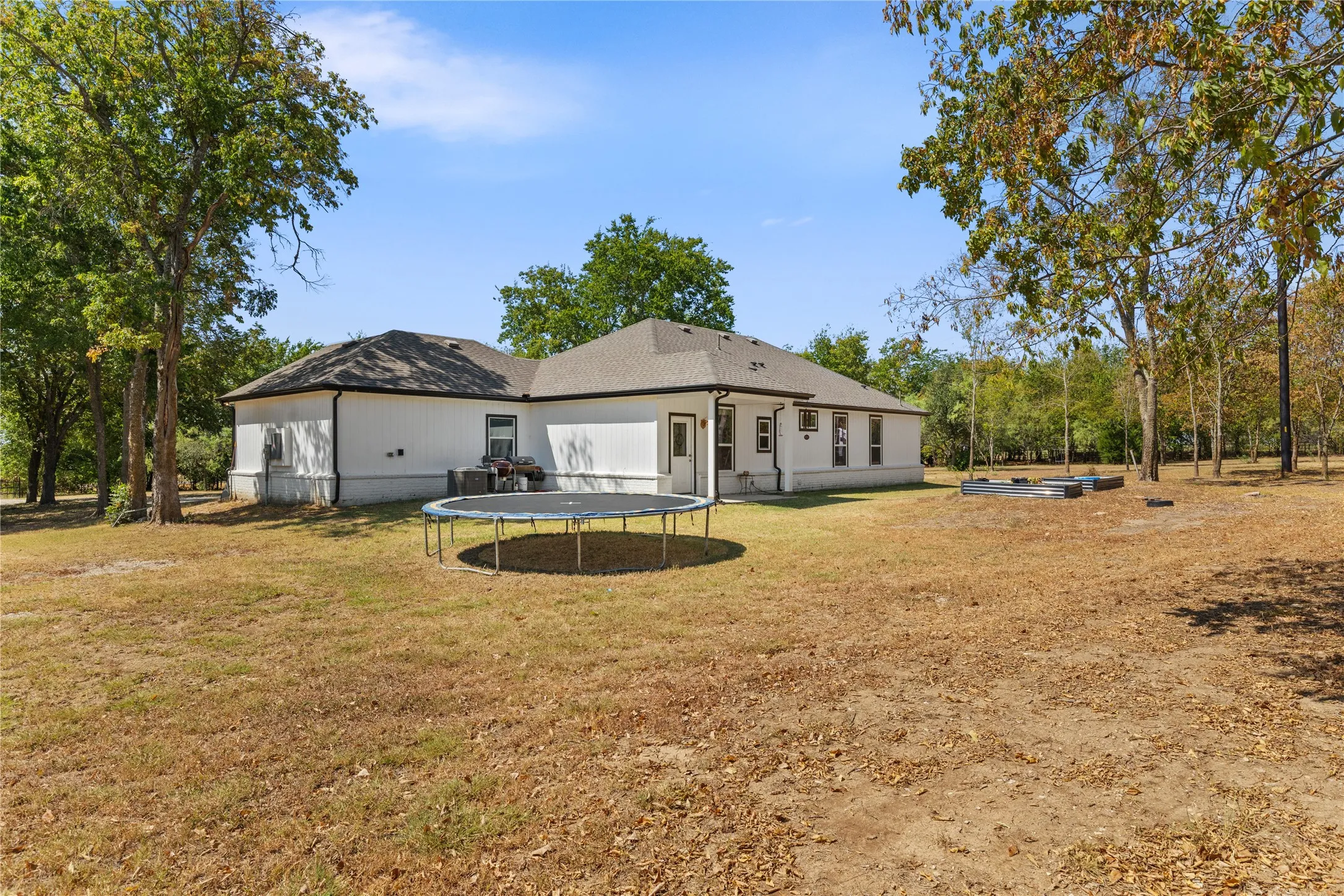 Expansive rear yard with mature trees and raised garden beds