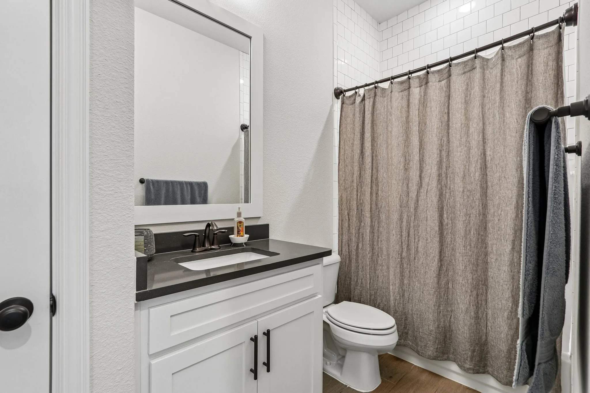 White vanity with dark countertop, rectangular undermount sink, and dark bronze fixtures