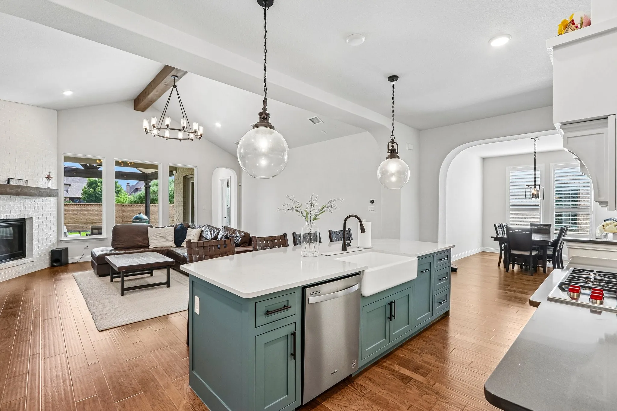Kitchen island with an integrated farmhouse sink, stainless steel dishwasher, and pendant lighting